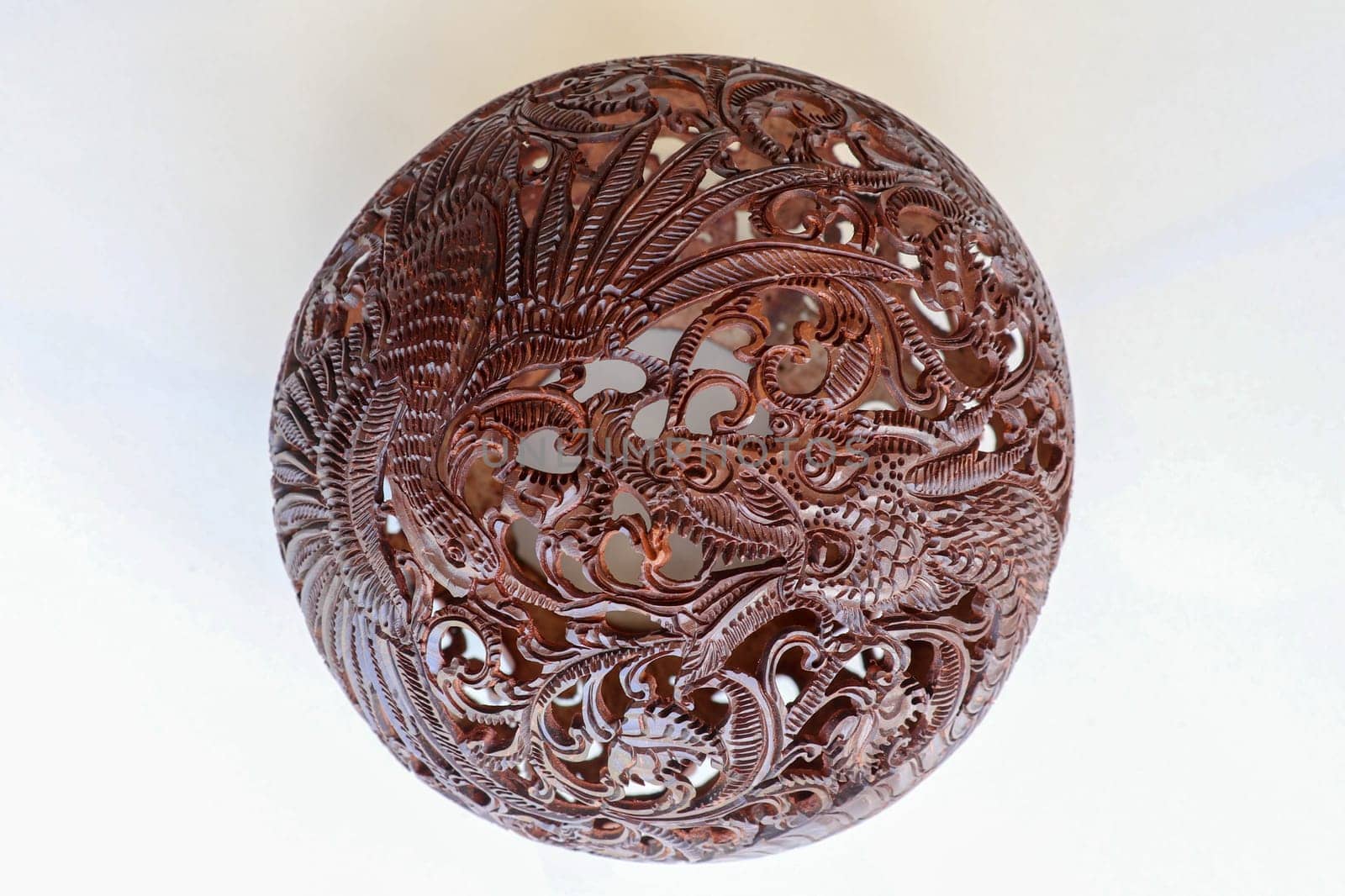 Close up ornamental shell for candle. Carved Souvenir from Coconut. Traditional handicraft on Bali, Indonesia. Hand carved ornaments with animal and plant motifs on the coconut shell. Mystical dragon.