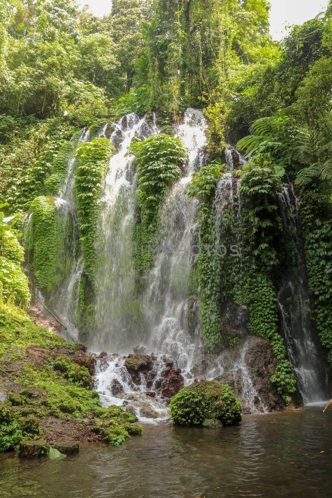 Spray waterfall in Bali island, Indonesia. Scenic waterfall high in the mountains. Having fun in the wild nature. Waterfalls in jungle. Bali Travel Concept. Lifestyle. Travel photography.