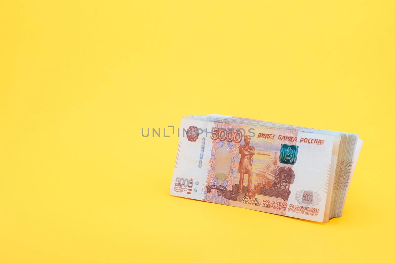 A pack of five thousandth bills on a yellow background
