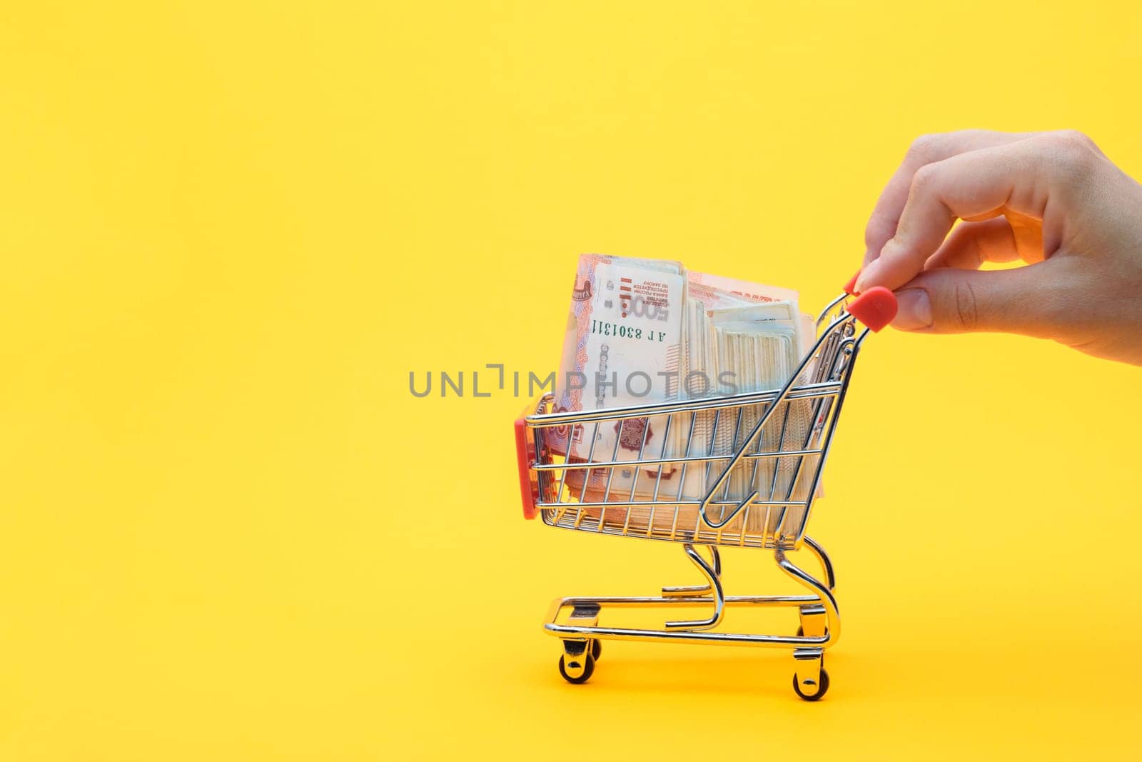 Hand carries a grocery cart with a pack of five thousandth Russian rubles