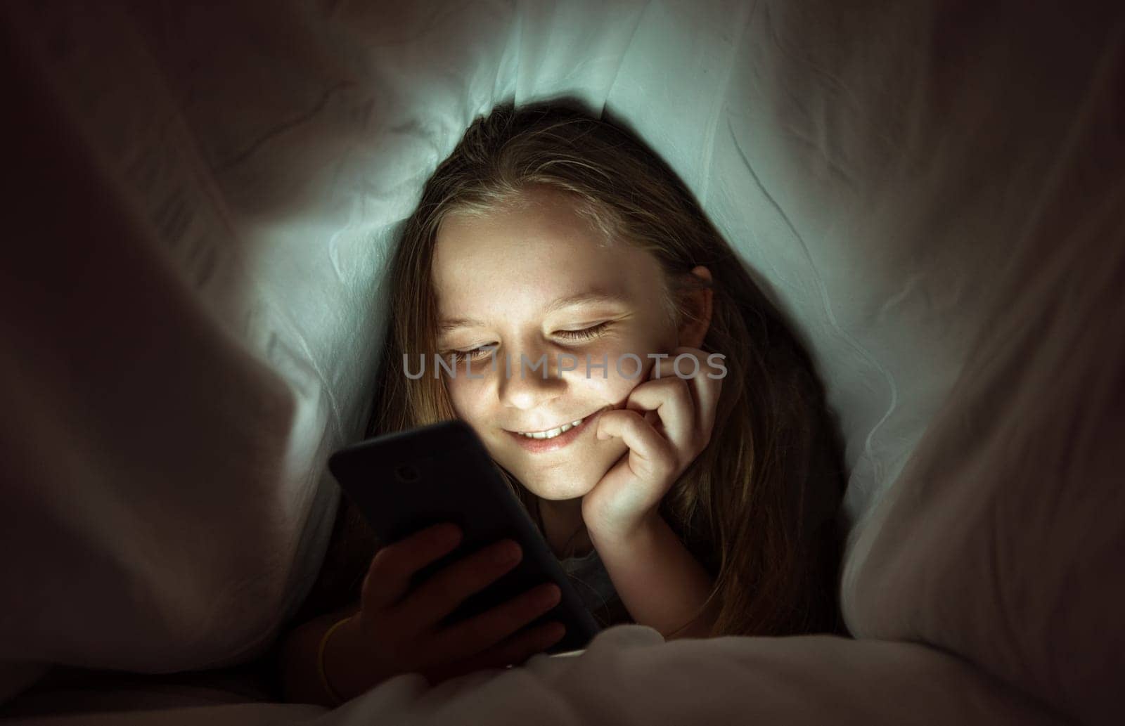 Young girl using a phone in bed