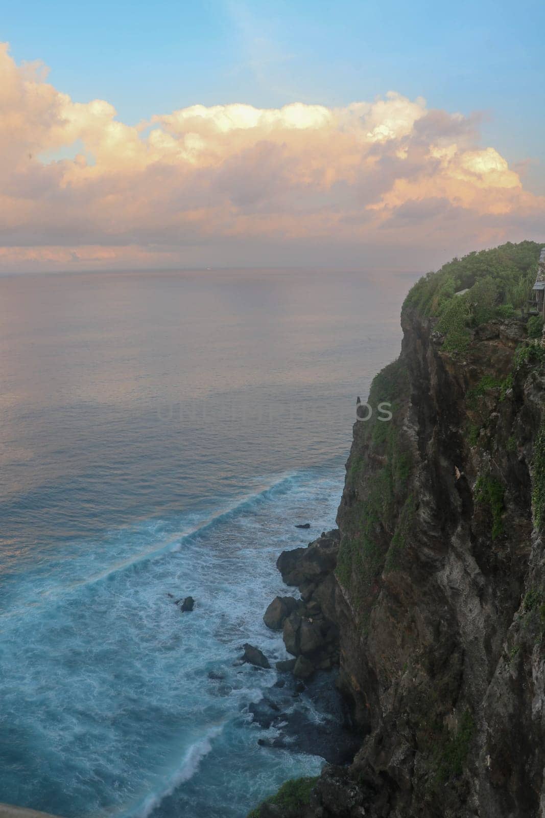 Beautiful Panoramic view of an Iconic Famous Place, Uluwatu Temple, during a vibrant summer sunrise. Amazing views at Pura Luhur Uluwatu temple in Bali Island. Nice colourful sunset with clouds.