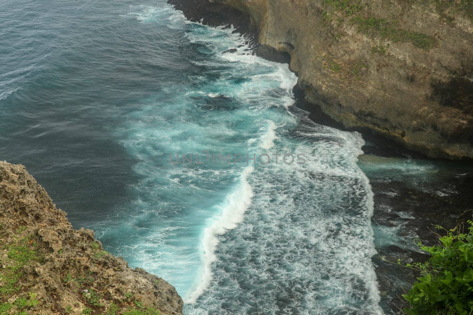 Overview panorama ocean shore, cliff. Sunset. Bali. Overwhelmed scene the flower and green-capped vertical cliff over the Indian ocean. South of Bali island, Pura Luhur Uluwatu Temple. Indonesia.