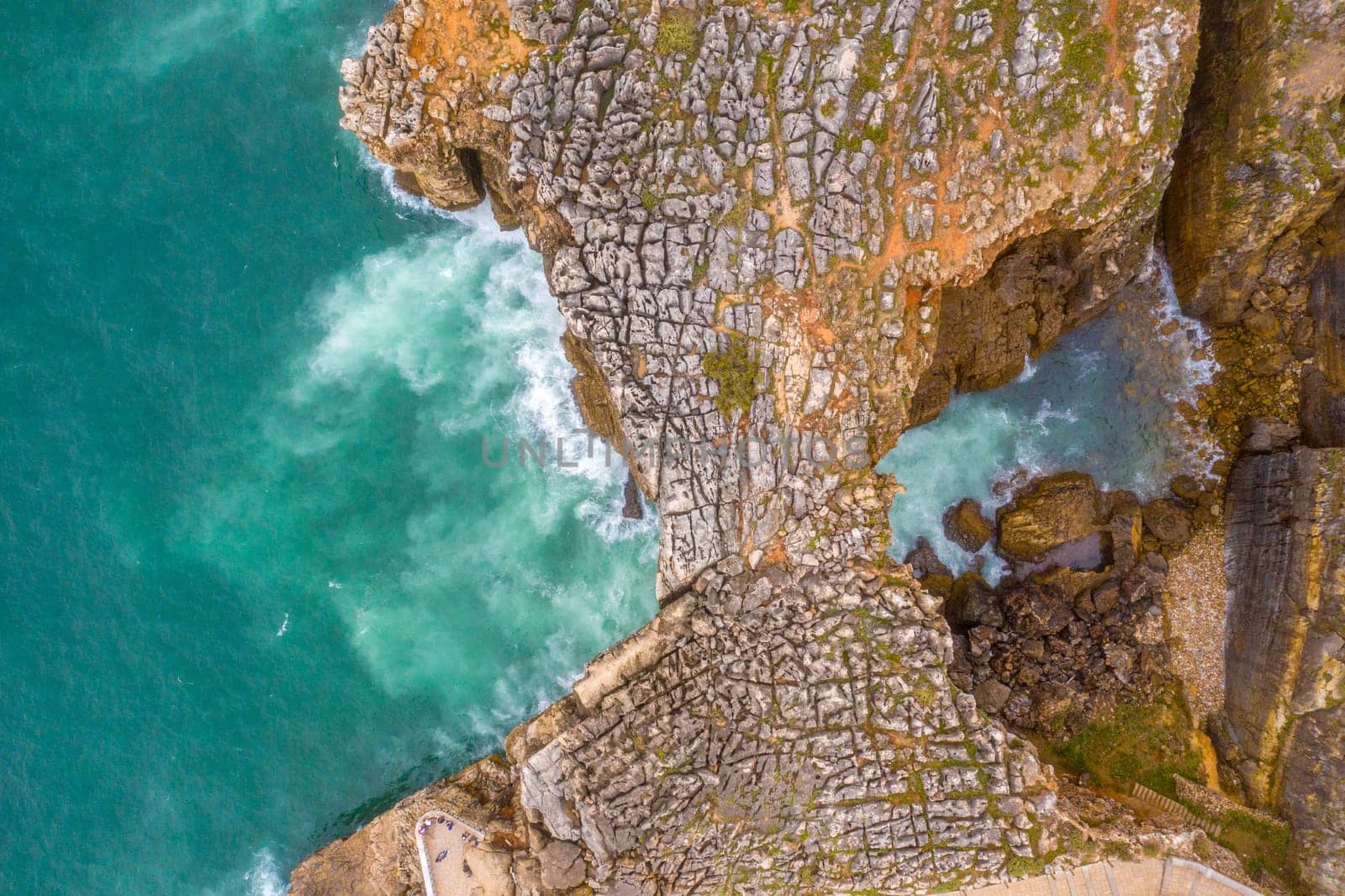 Wild turquoise ocean waters at the rocky coast of Boca do Inferno in Portugal - aerial drone footage