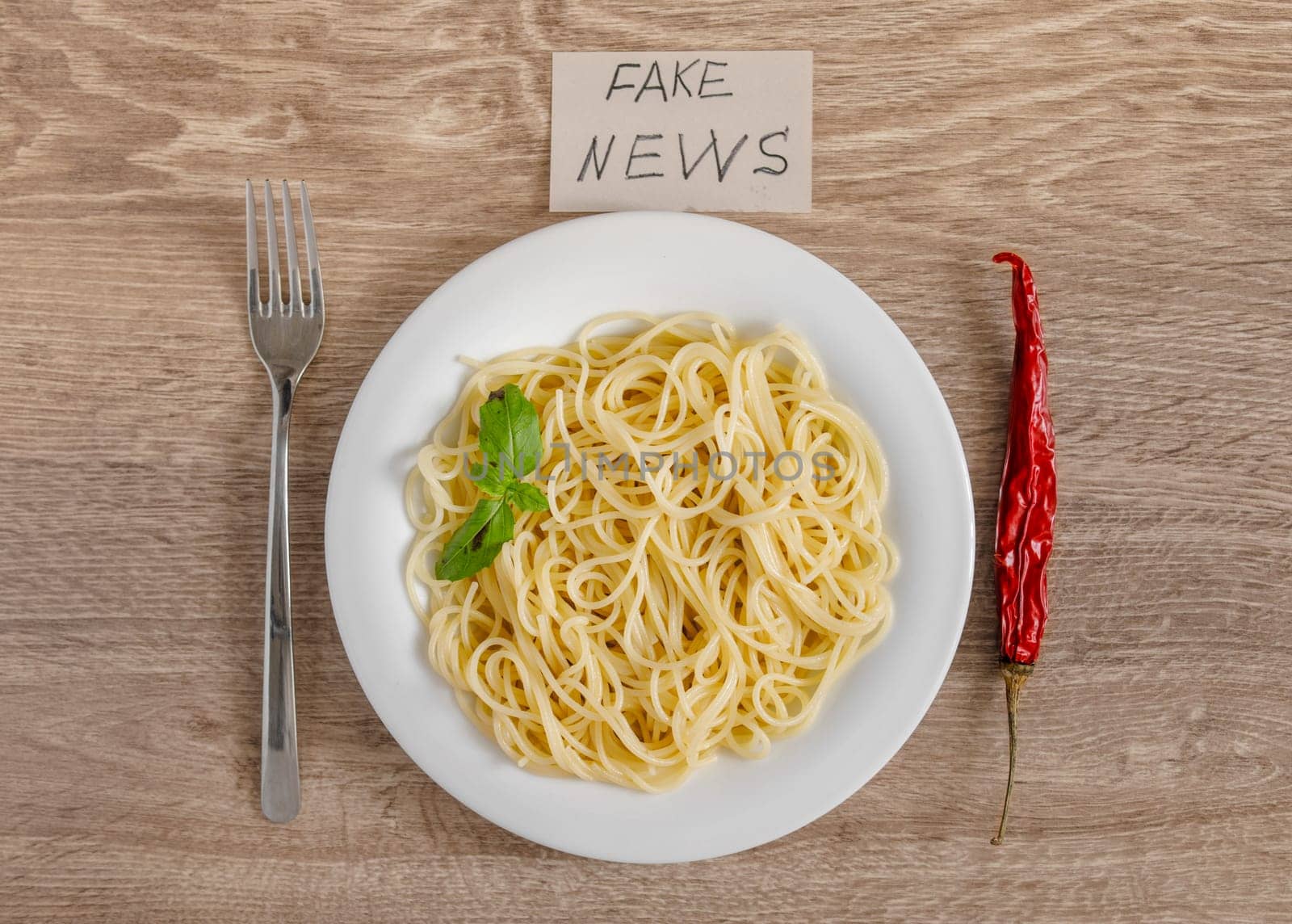 Spaghetti with a sprig of basil and chili pepper as a fake news concept