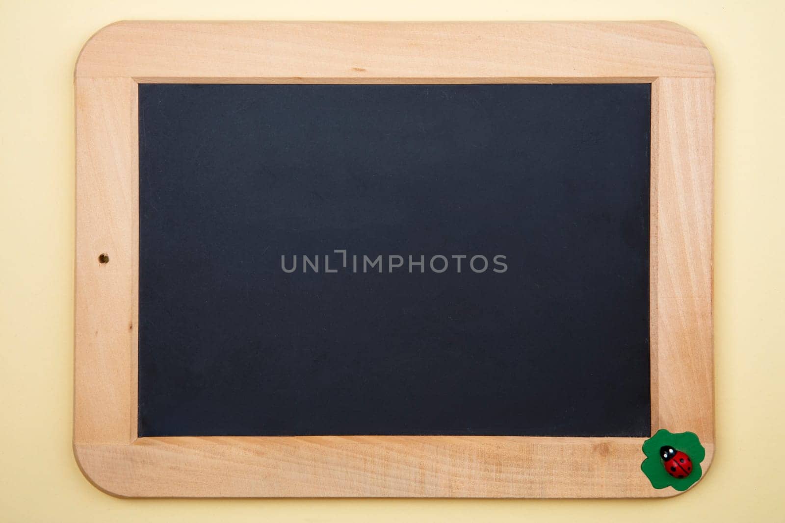 Decorative Blackboard with little wooden junic beetle on yellow background