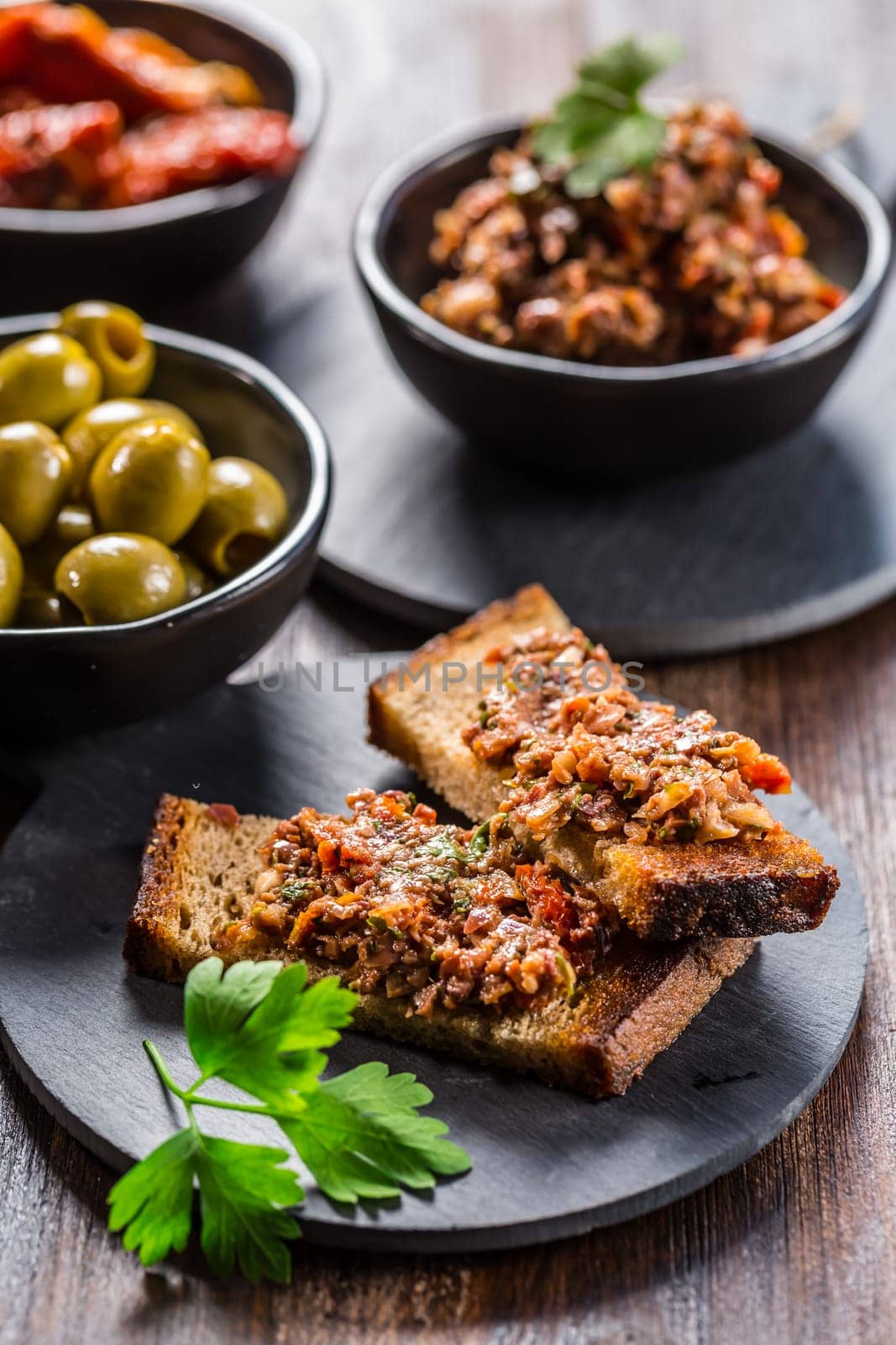 Crispy crostini with tapenade and ingredients. Tapenade - delicious olive paste from France.