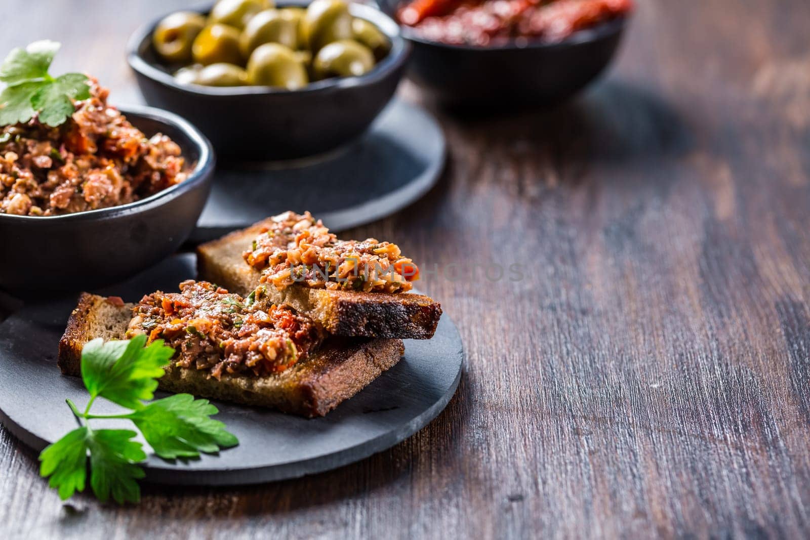 Crispy crostini with tapenade and ingredients. Tapenade - delicious olive paste from France.