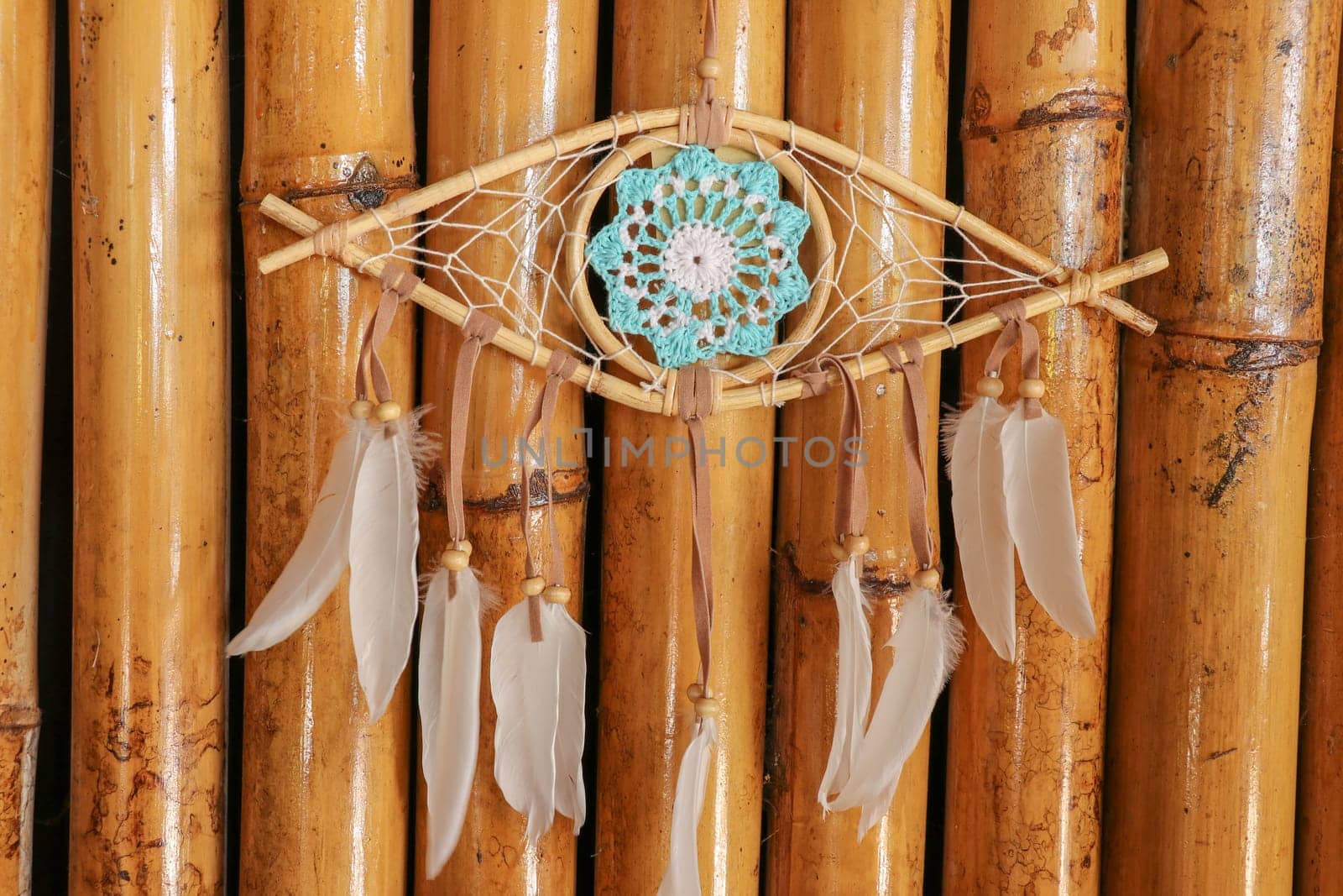 god eye of providence dreamcatcher with white feathers on a wodden background.