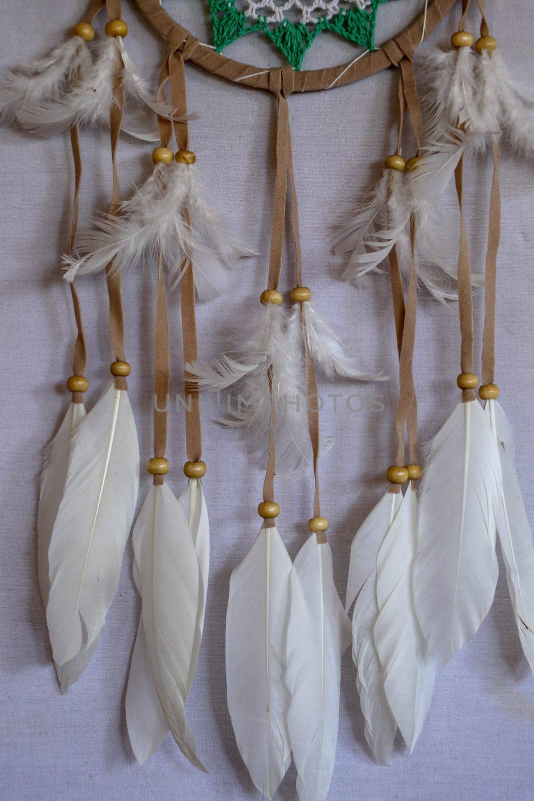 Closeup of white dream catcher a small white hoop decorated with feathers and beads.