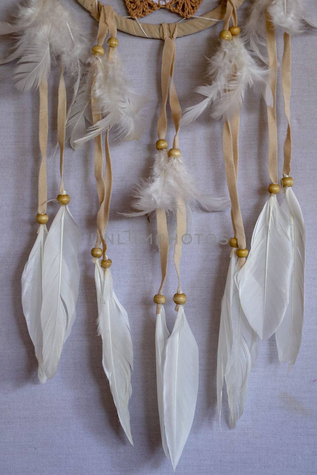 Closeup of white dream catcher a small white hoop decorated with feathers and beads.
