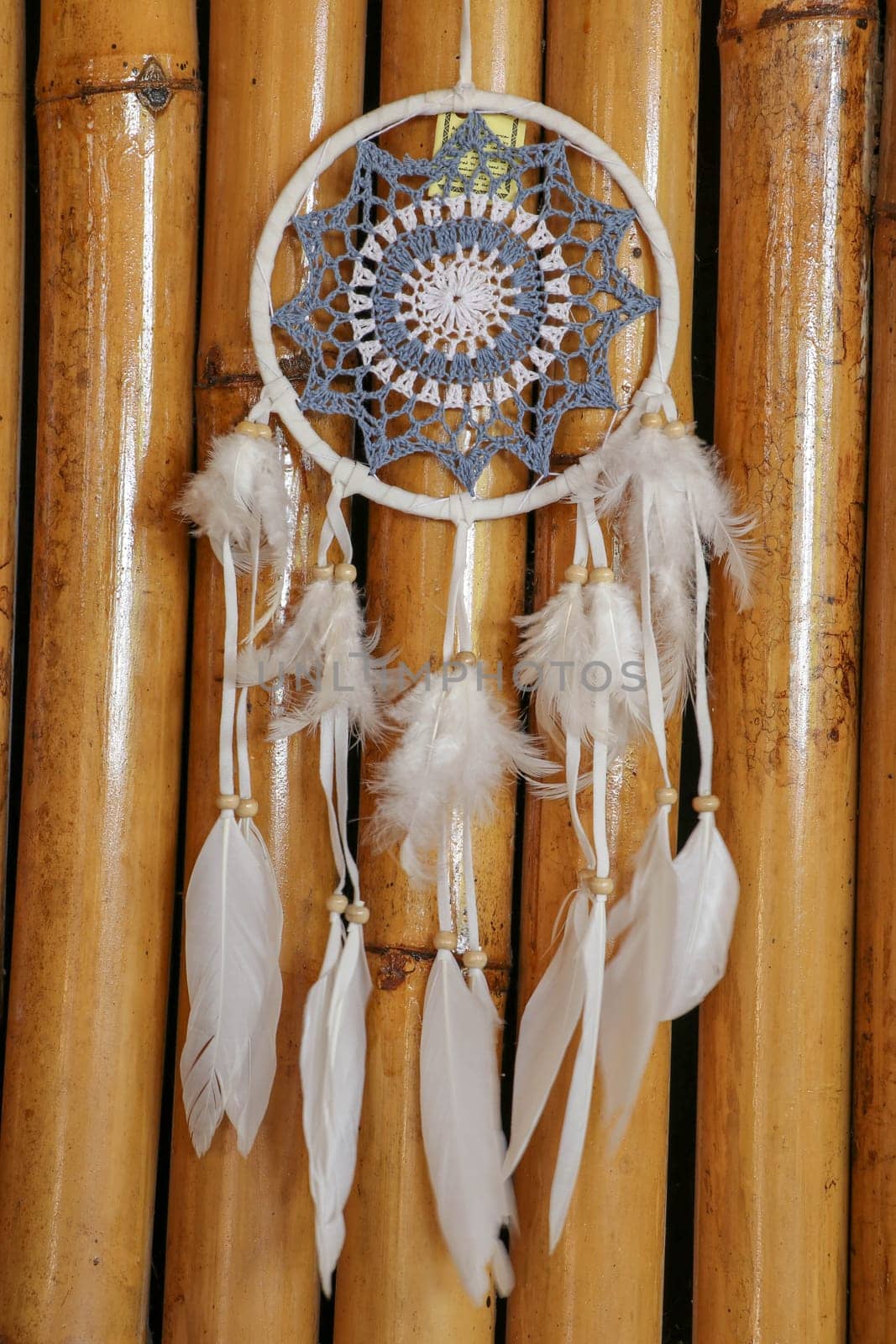 Blue Dreamcatcher with feathers and beads isolated on a wodden background.