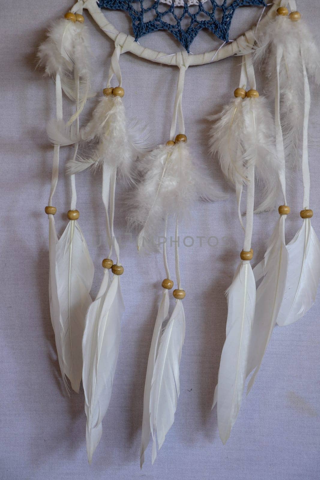 Closeup of white dream catcher a small white hoop decorated with feathers and beads.