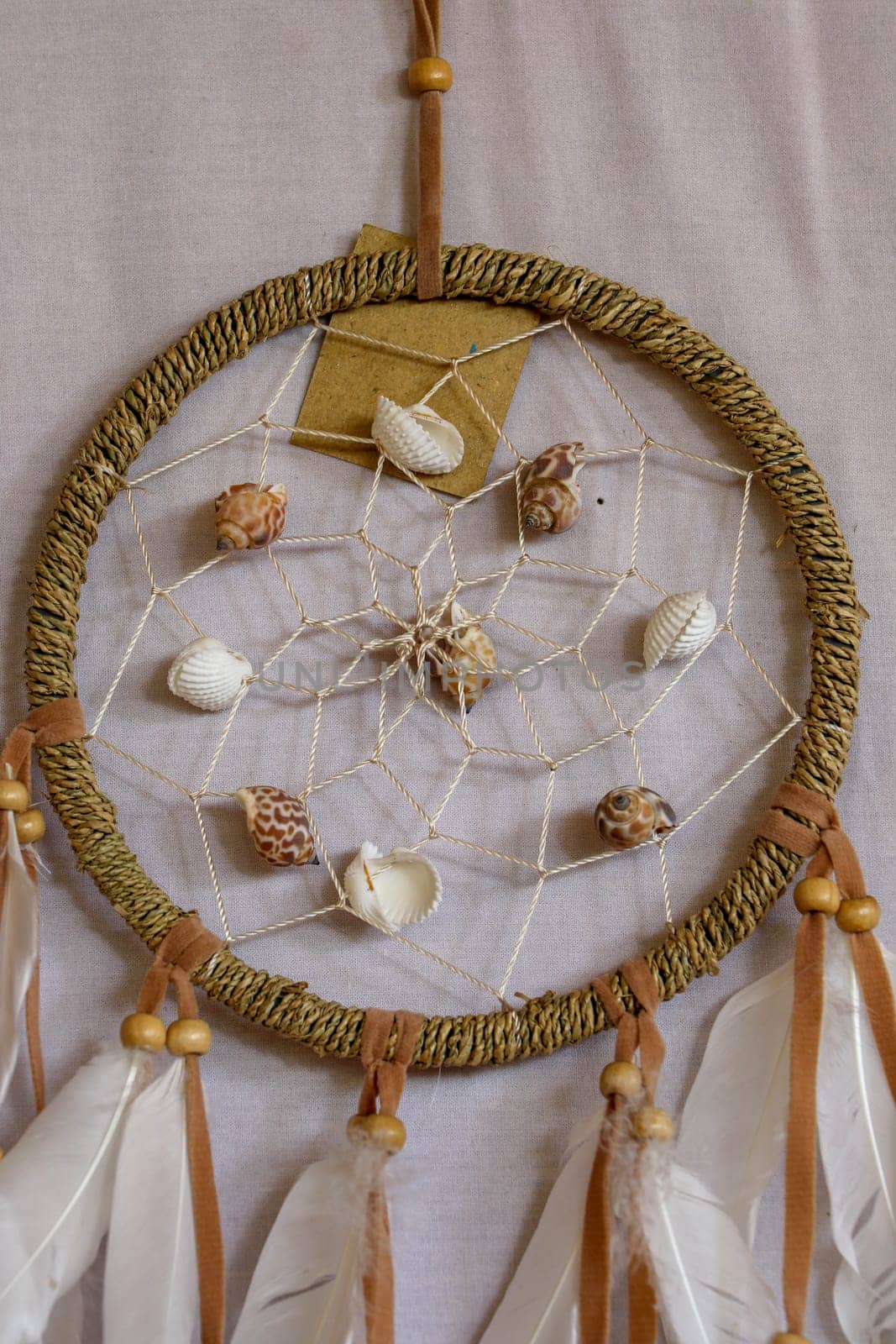 sea shell decoration. dream catcher. Handmade pink native american dream catcher on background of rocks and lake. Tribal elements, feathers, shells, lace