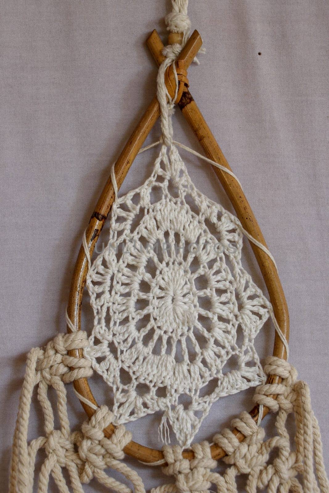 Beige crochet doily dream catcher close up on gray textured background. Texture of concrete, white background.
