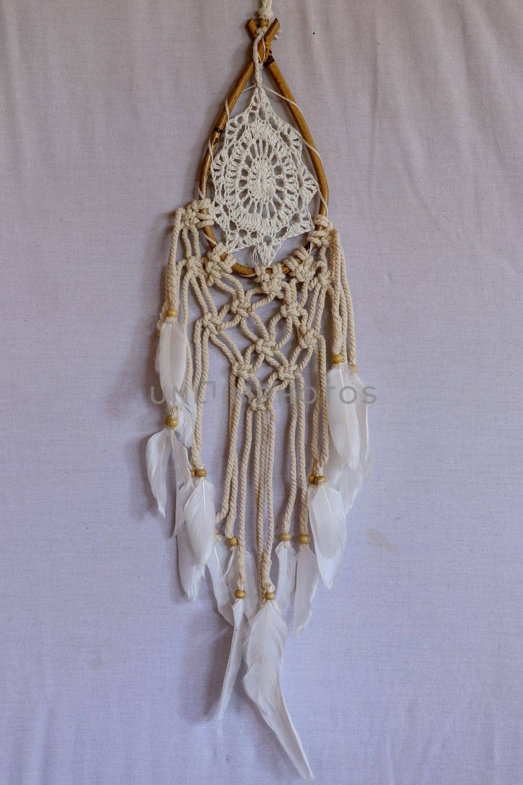Beige crochet doily dream catcher close up on gray textured background. Texture of concrete, white background.
