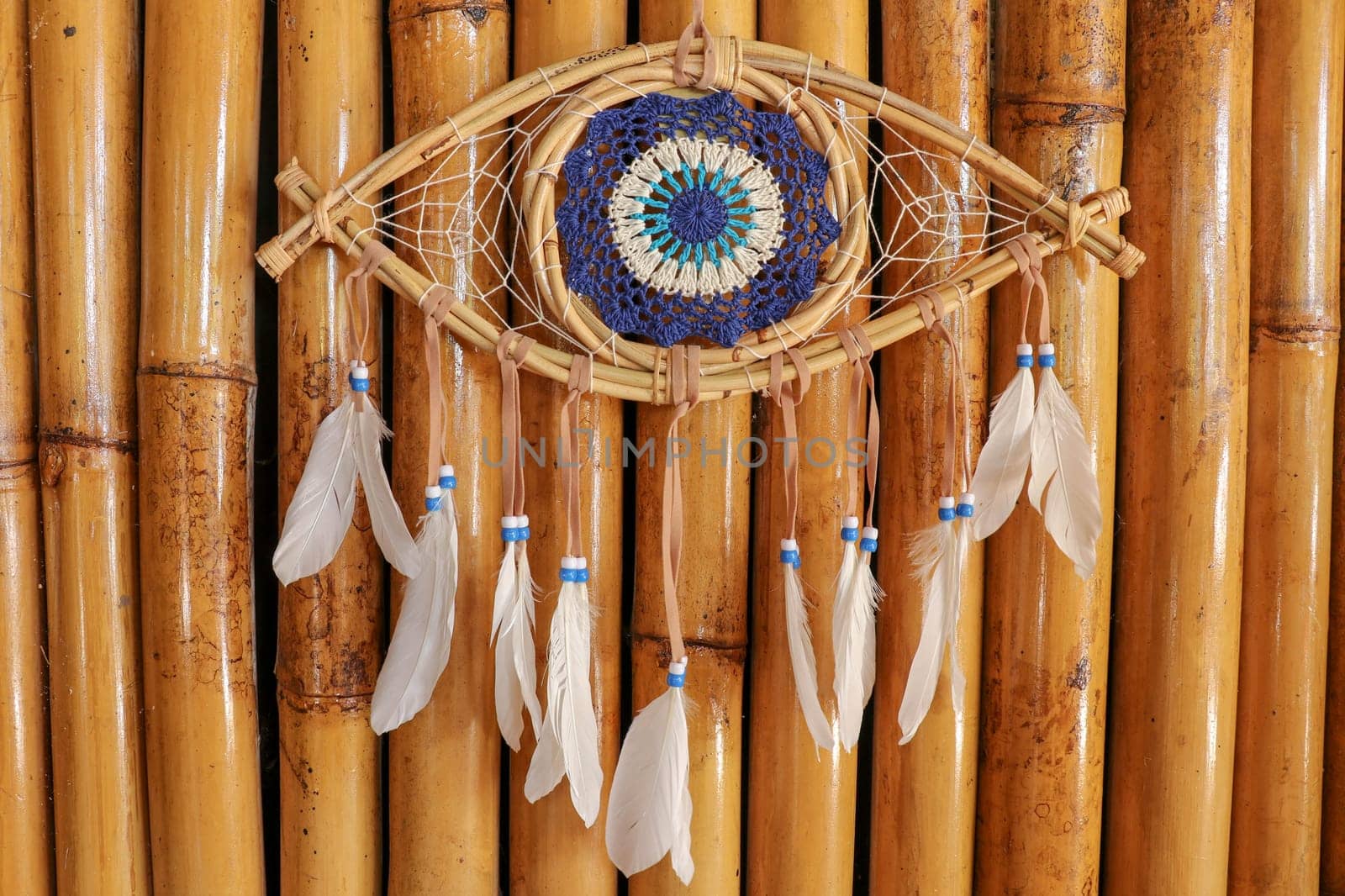 god eye of providence dreamcatcher with white feathers on a wodden background.
