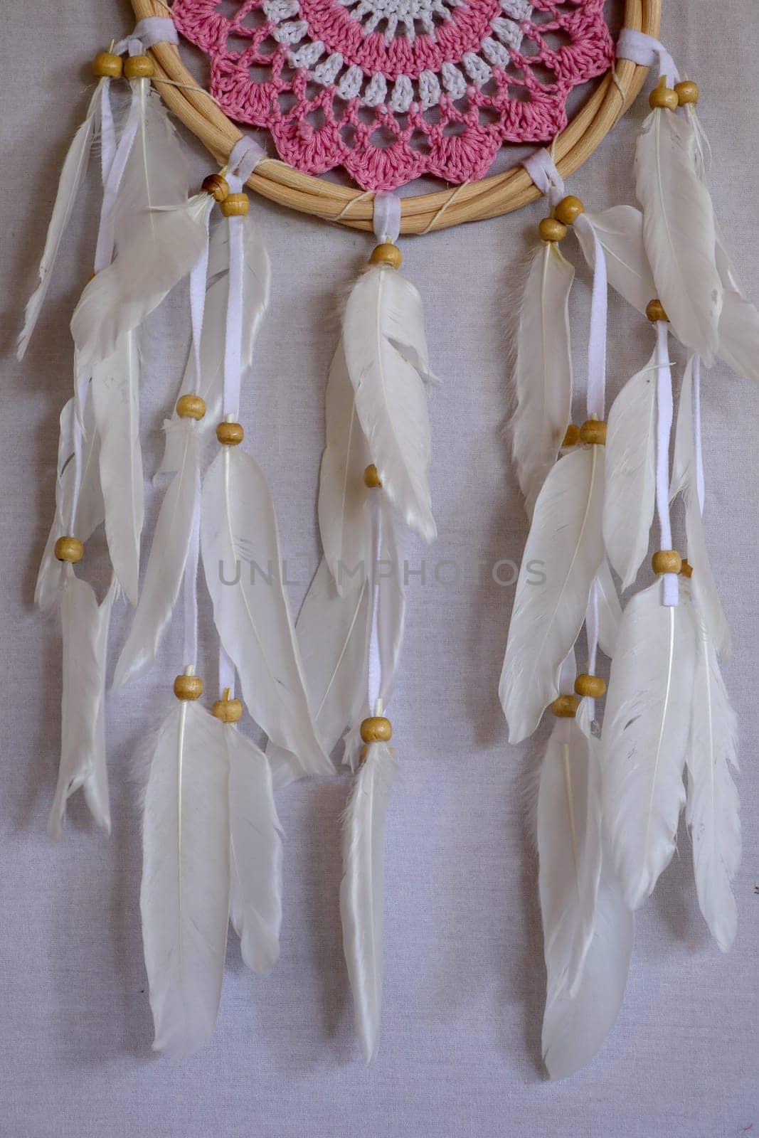 Closeup of white dream catcher a small white hoop decorated with feathers and beads.