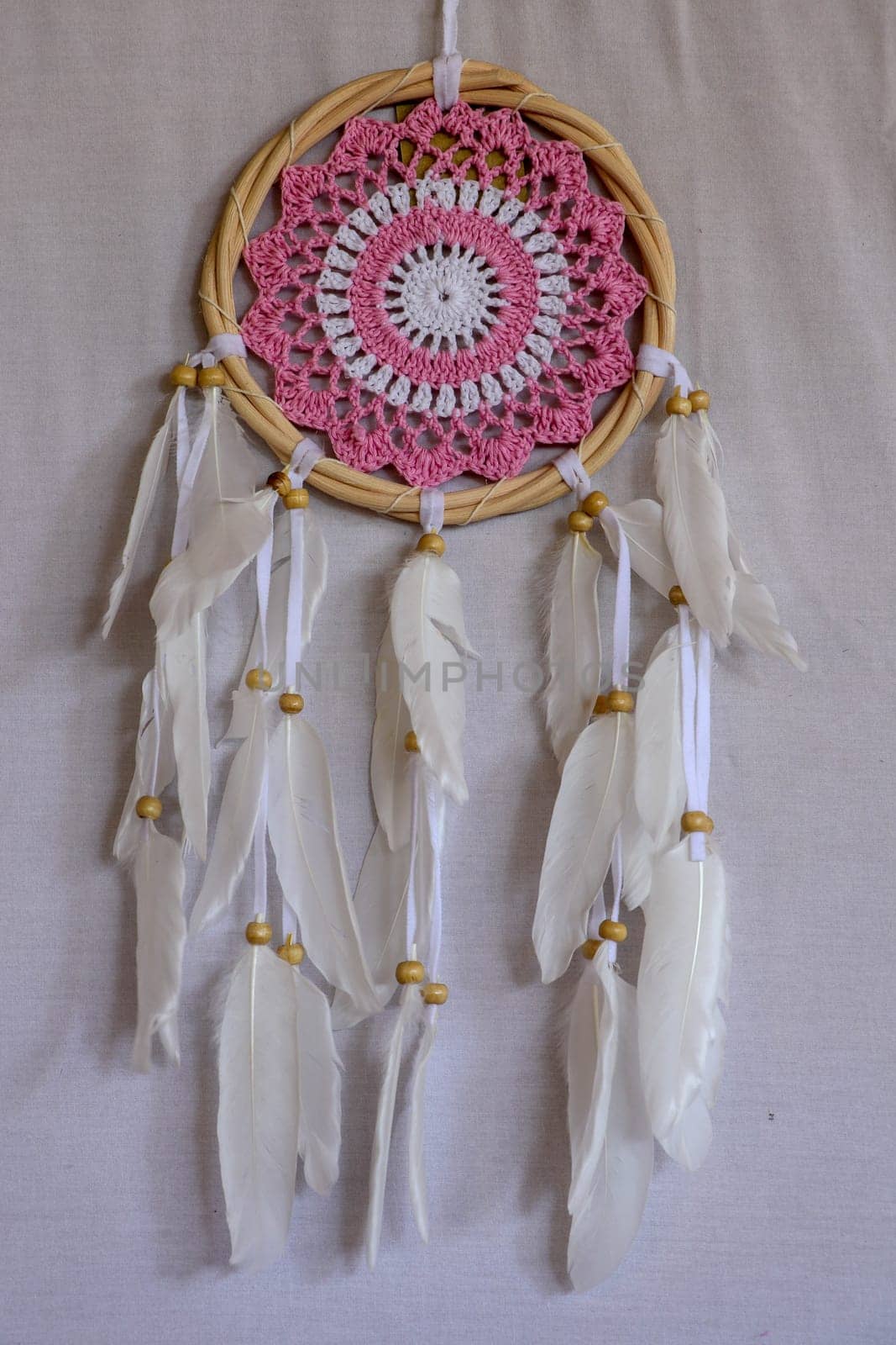 Pink ash crochet doily dream catcher close up on dark gray textured background. Texture of concrete, copy space for text. White background.