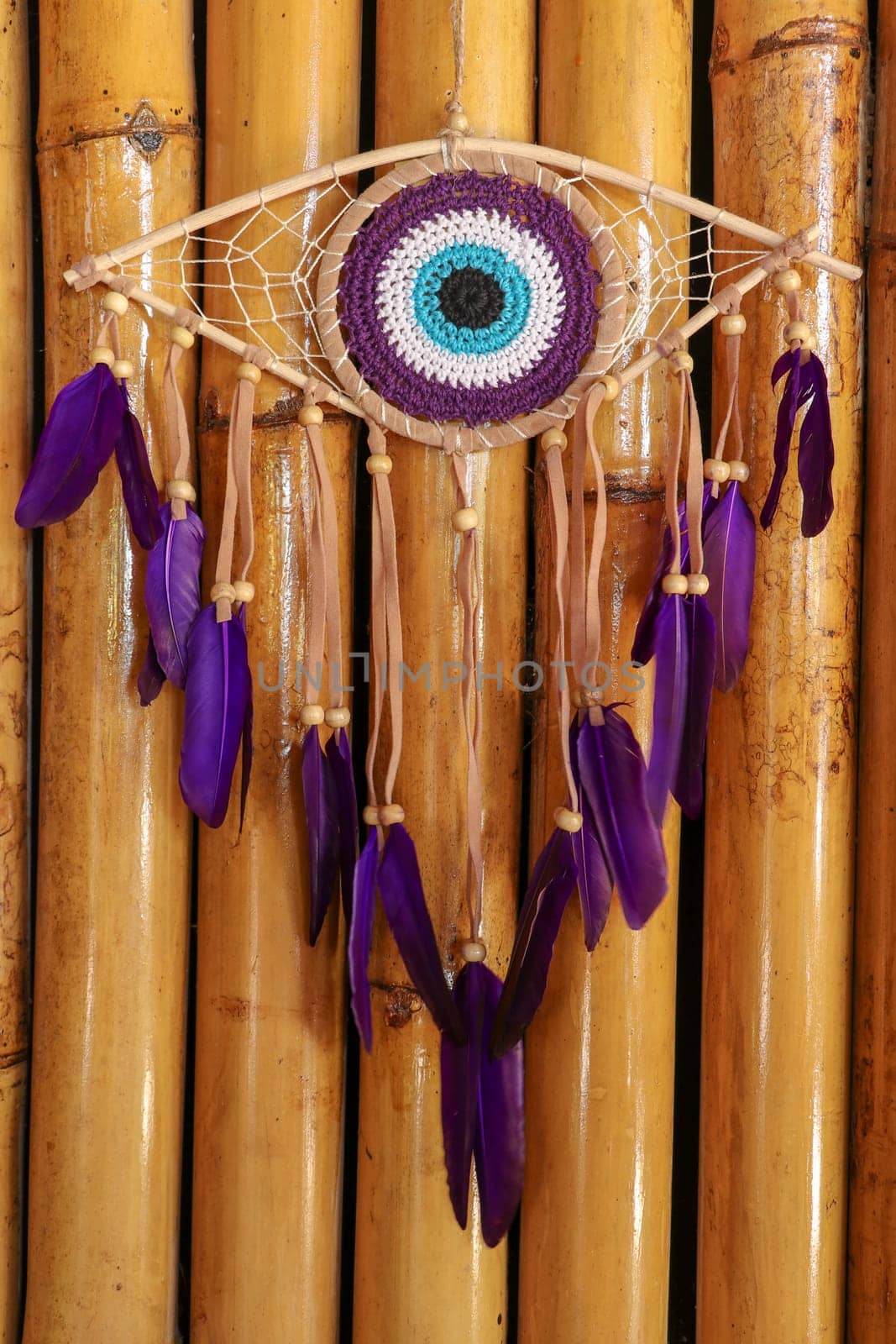 divine eye of providence dreamcatcher with colored feathers on a wodden background.
