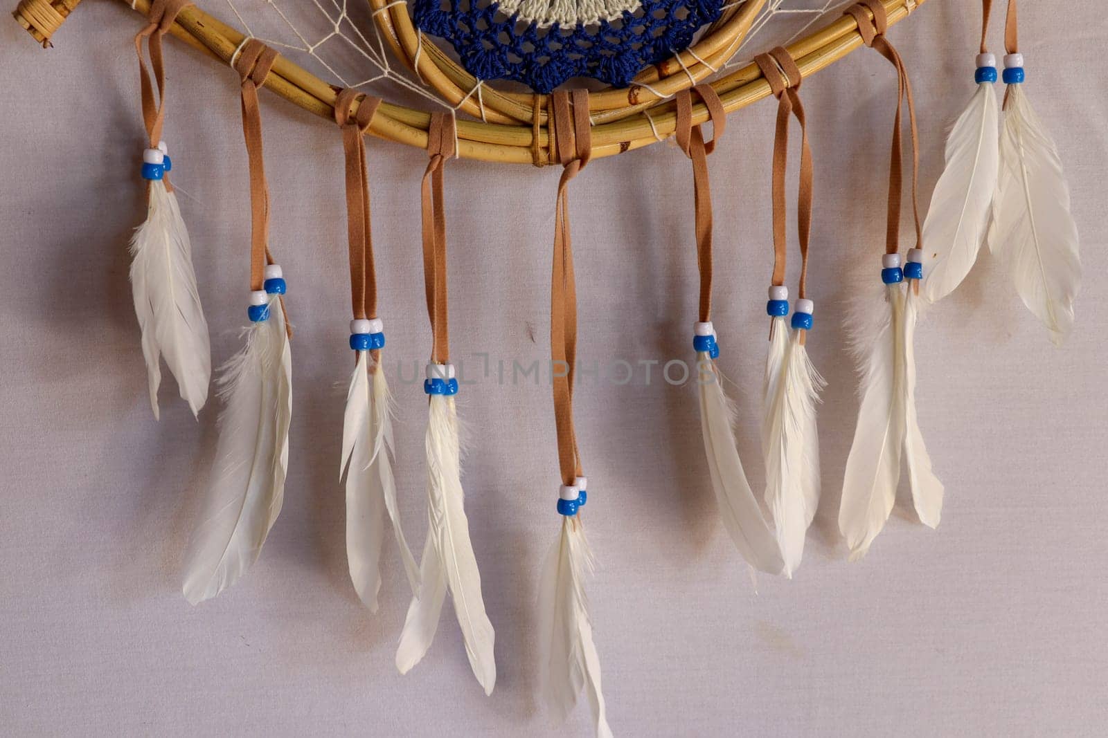 Closeup of white dream catcher a small white hoop decorated with feathers and beads.