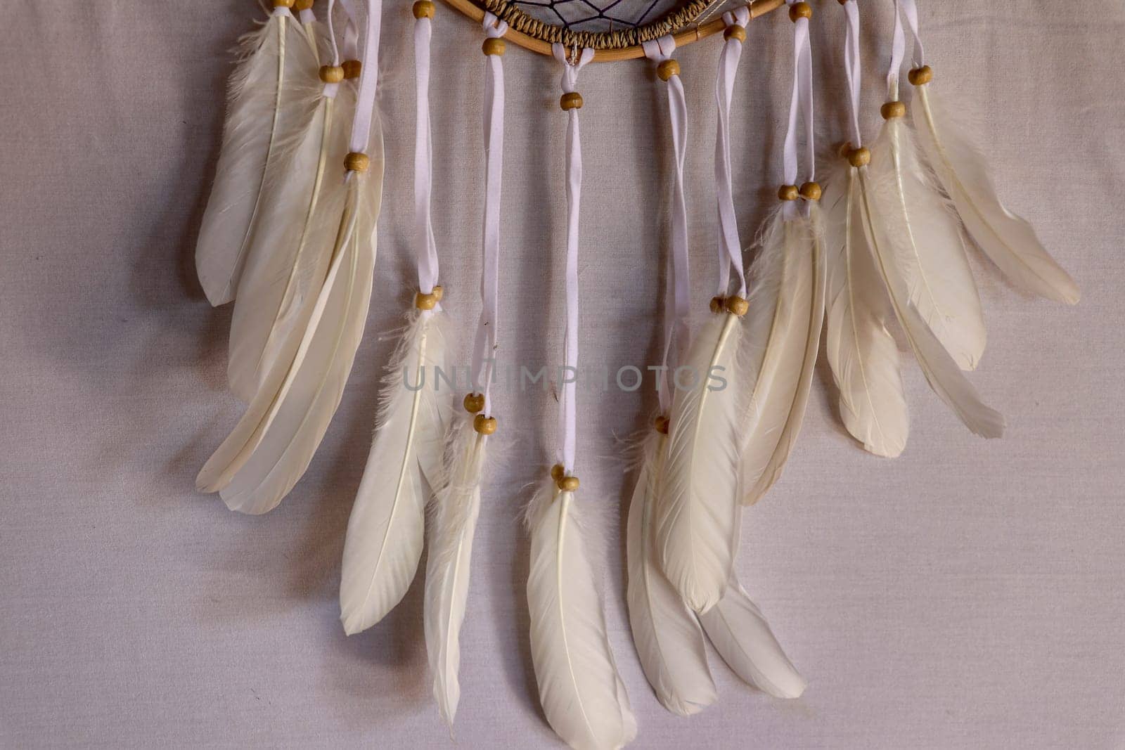 Closeup of white dream catcher a small white hoop decorated with feathers and beads.