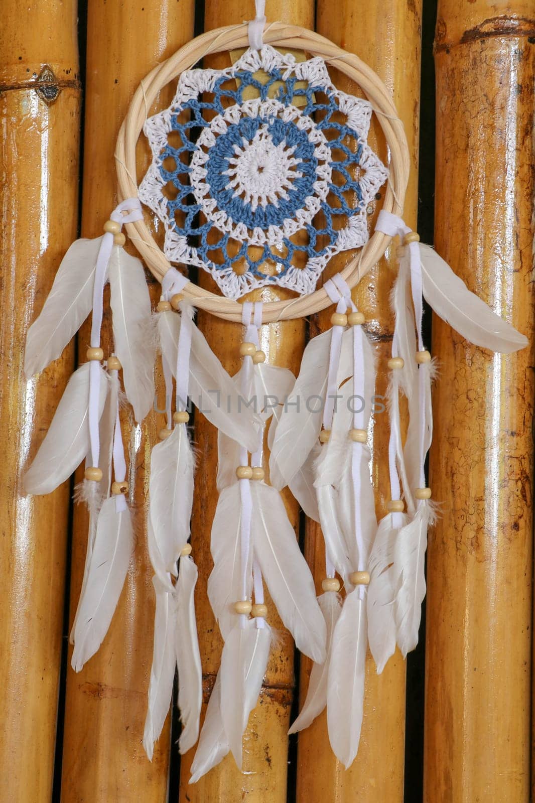 Blue Dreamcatcher with feathers and beads isolated on a wodden background.
