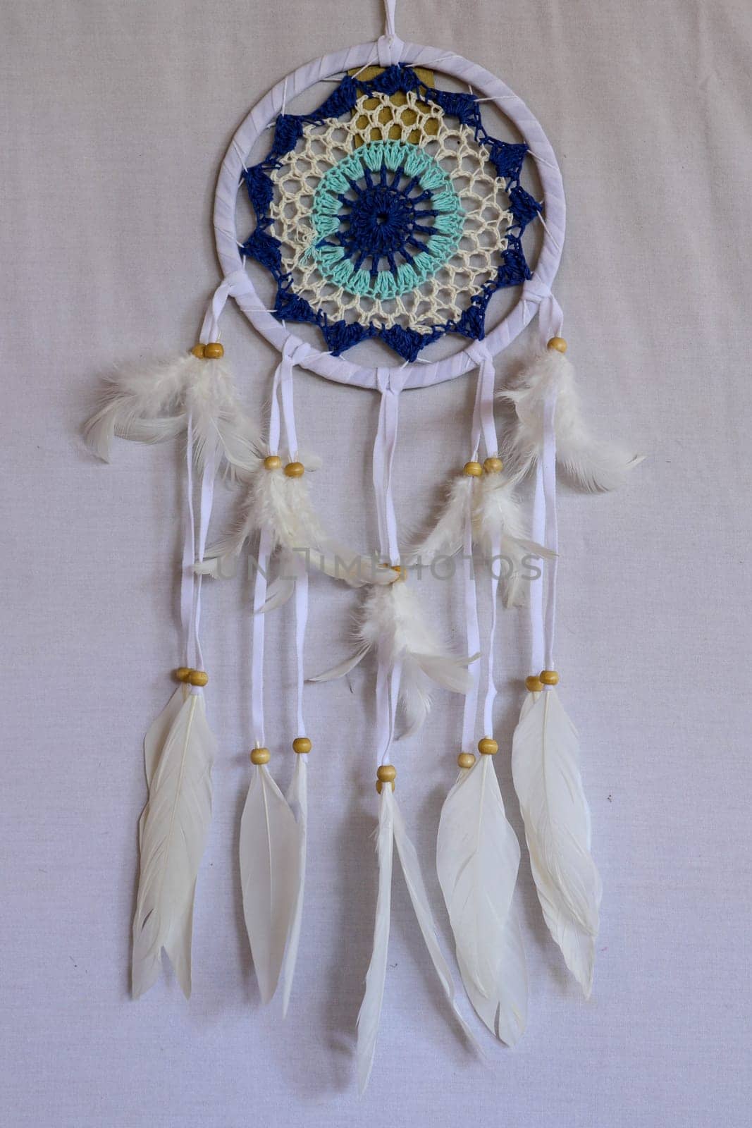 Blue Dreamcatcher with feathers and beads isolated on a white background.