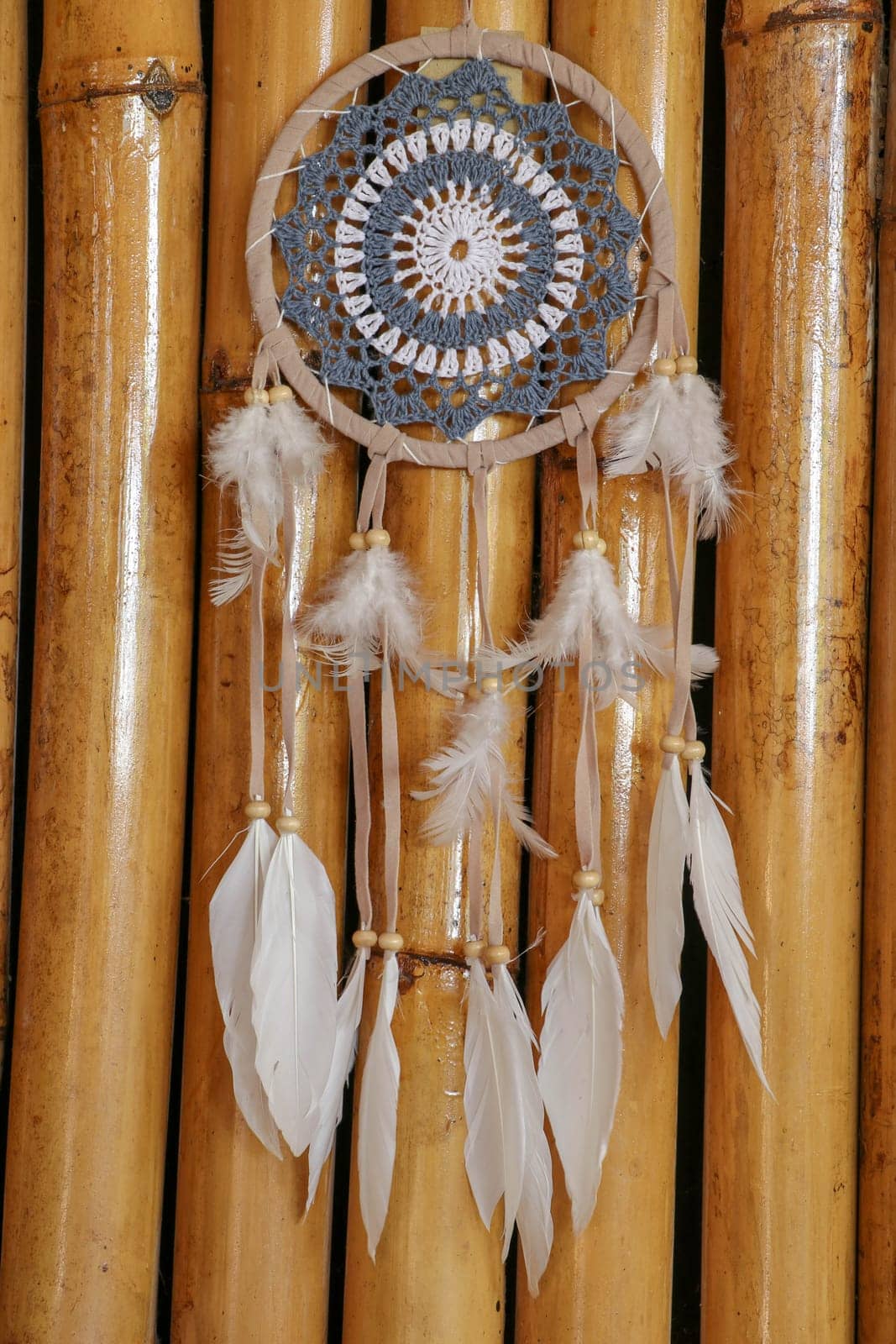 Blue Dreamcatcher with feathers and beads isolated on a wodden background.