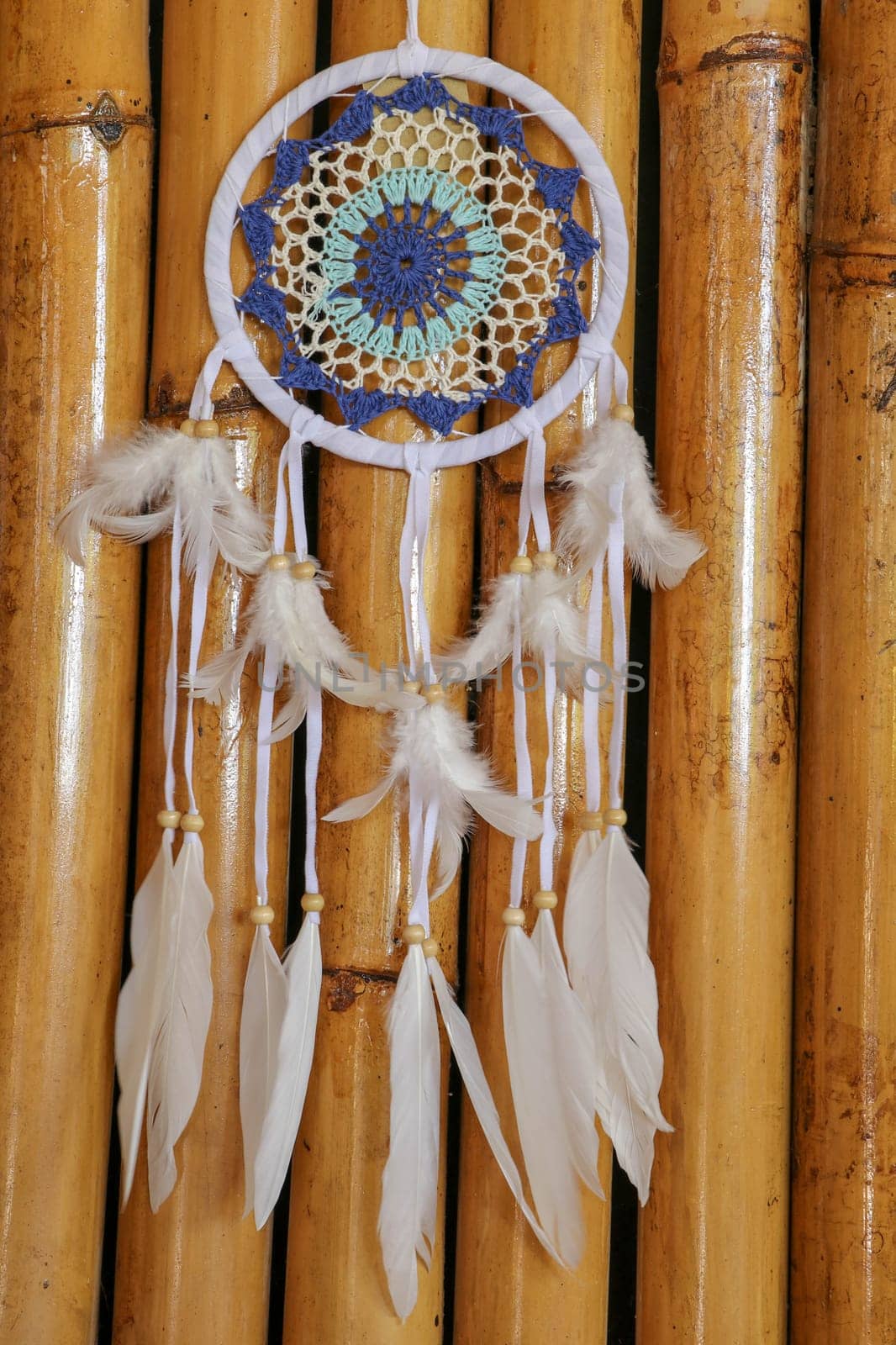 Blue Dreamcatcher with feathers and beads isolated on a wodden background.