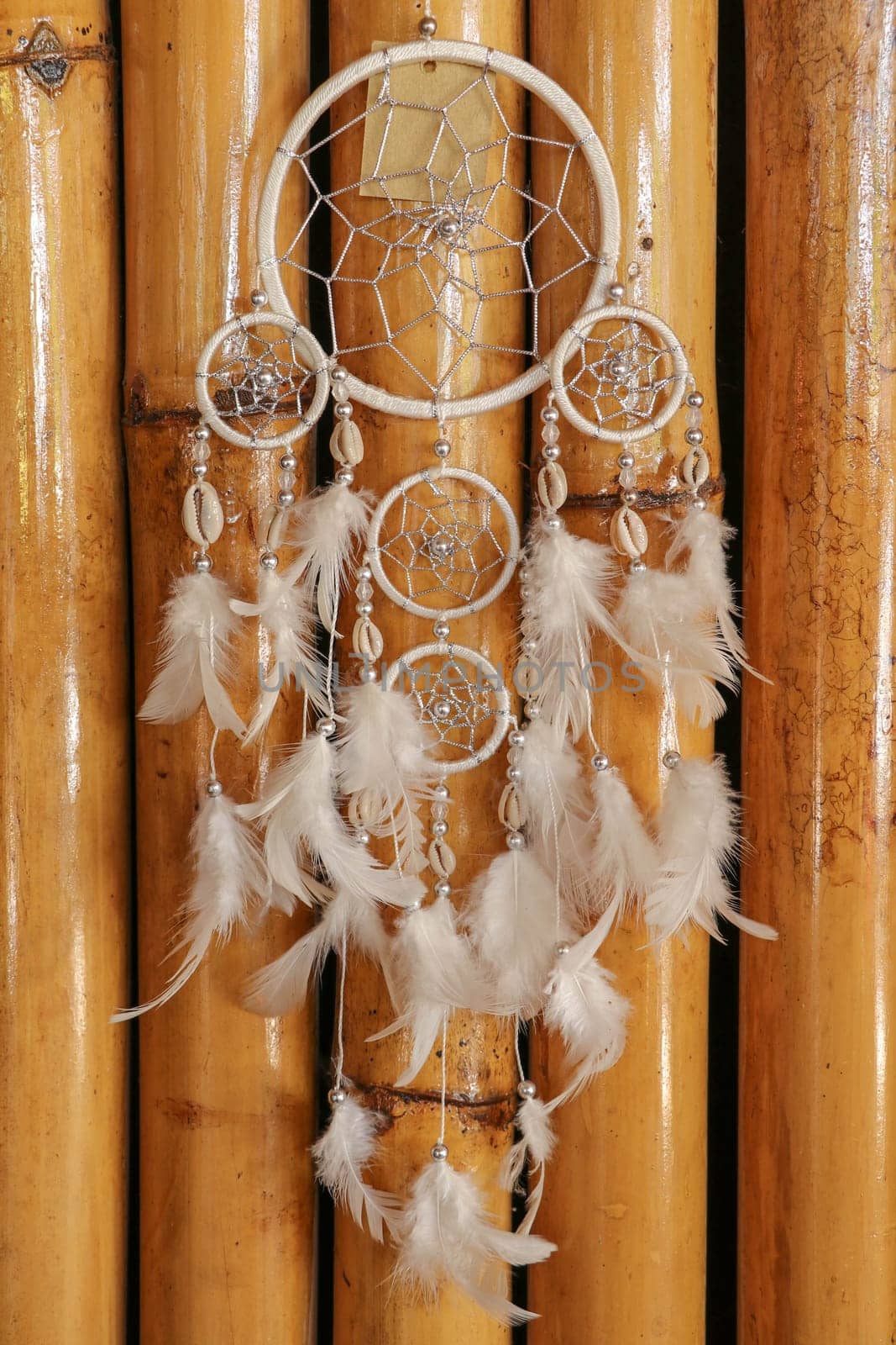 Dream catcher, decorated with white feathers and wooden beads, on a wooden surface. Dream catcher with wooden circle. Knitted Native American amulet with the symbol of Yin Yang on a wodden background.