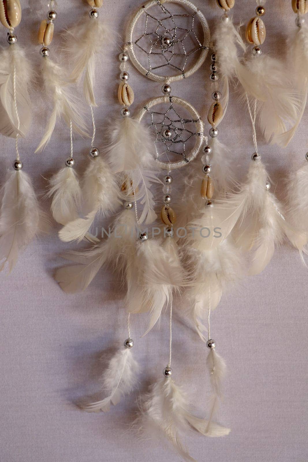 Closeup of white dream catcher a small white hoop decorated with feathers and beads.