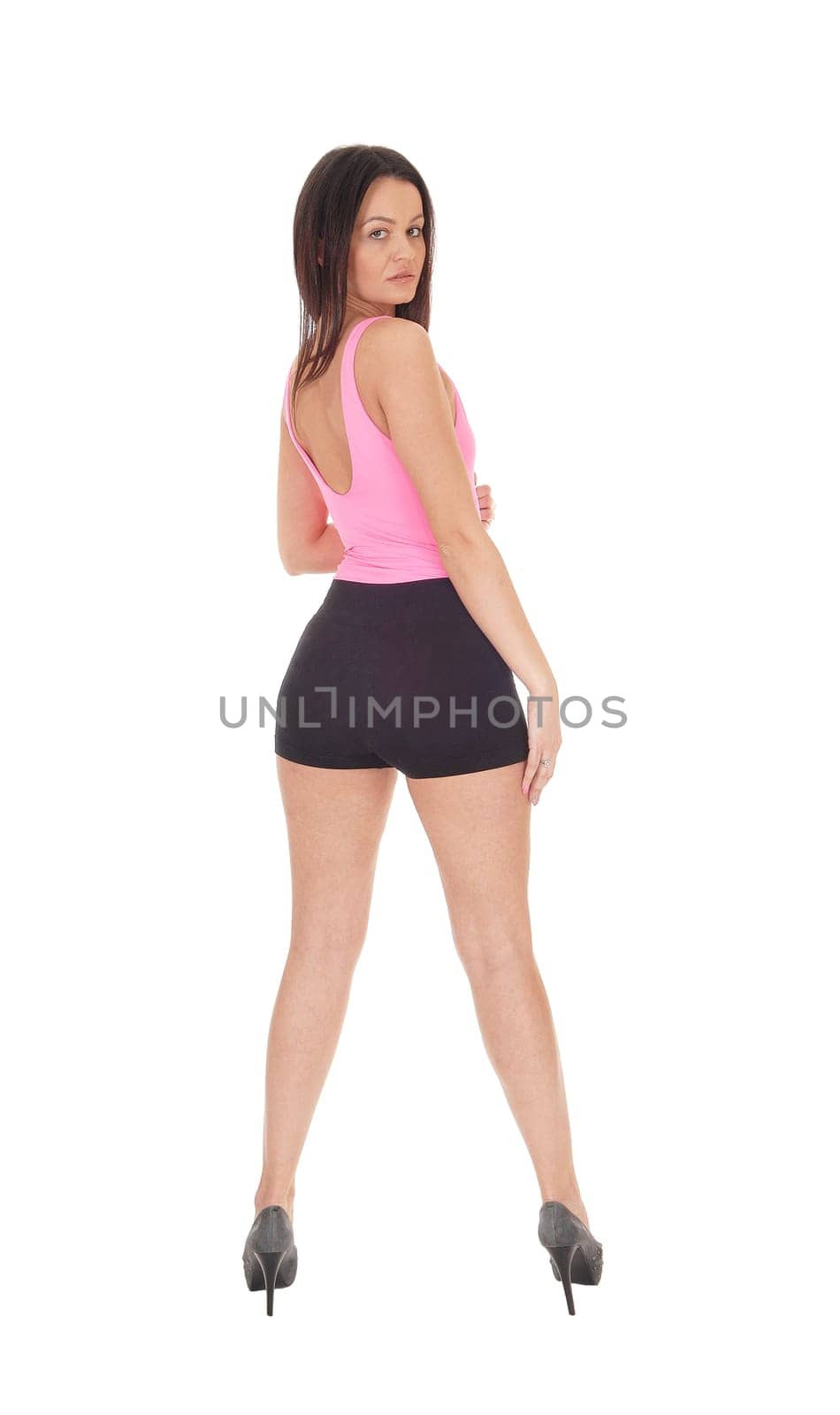 Beautiful slim young woman standing in the studio from the back looking.over her shoulder, isolated for white background.