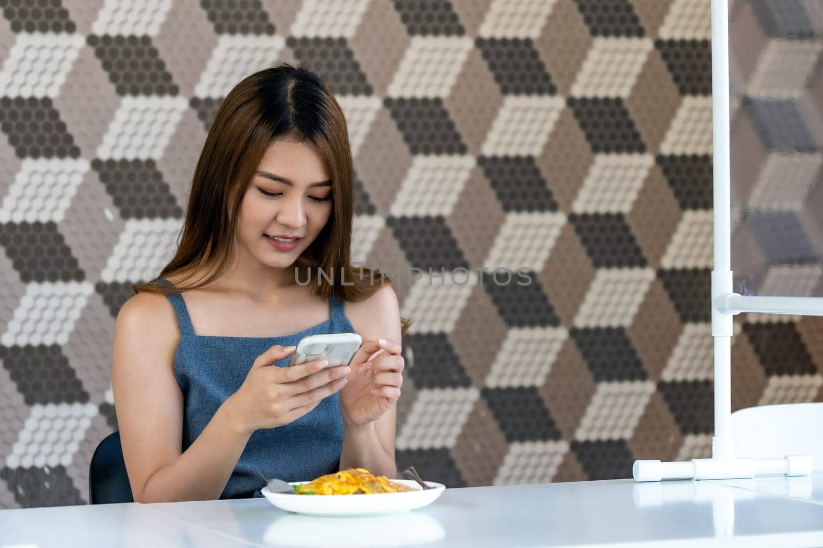 Portrait of asian influencer food blogger or vlog take food photo at new normal social distance restaurant with table shiled partition. Restaurant new normal lifestyle and food influencer concept.