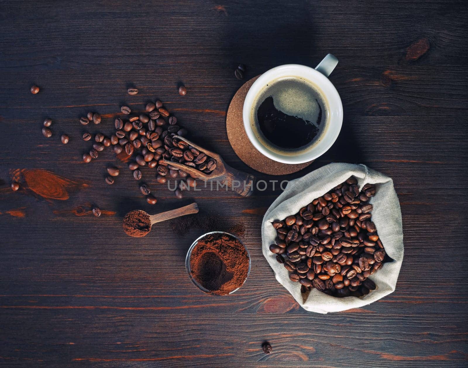 Photo of fresh tasty coffee on vintage wood table background. Coffee cup, coffee beans in canvas bag and ground powder. Top view. Flat lay.