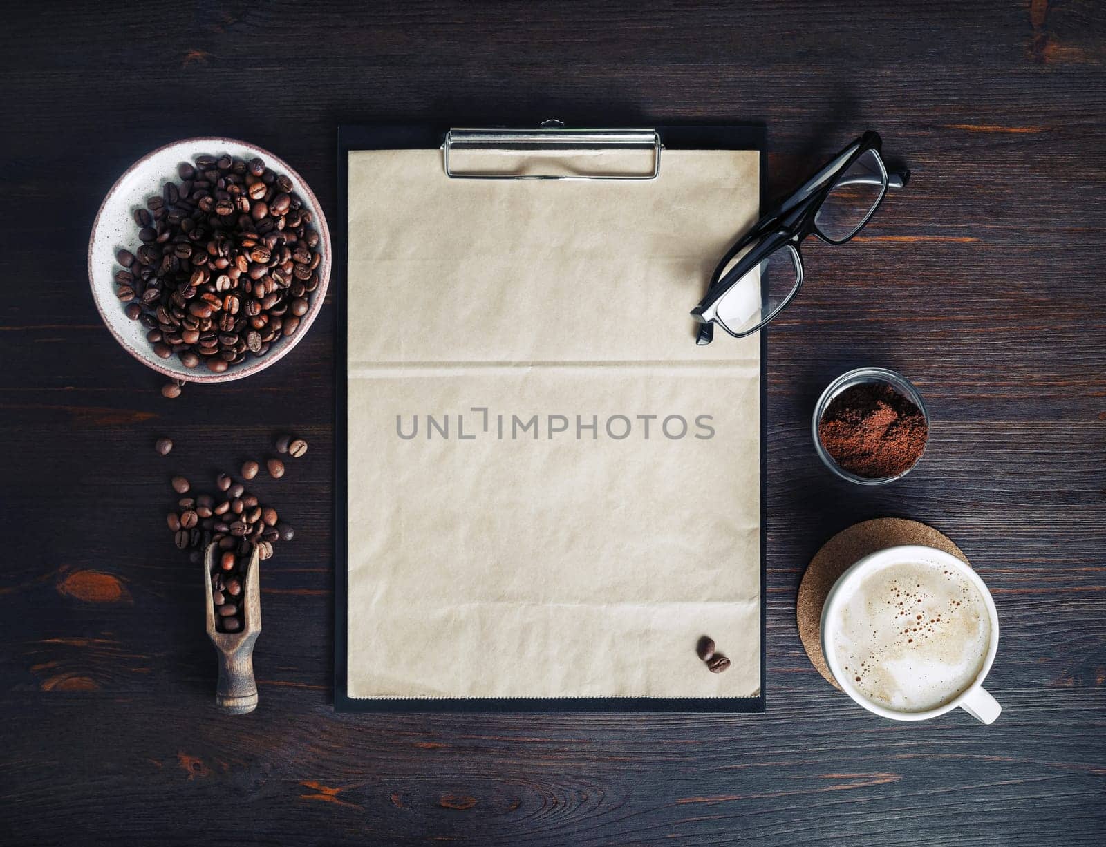 Coffee and blank menu. Clipboard with blank kraft letterhead, coffee cup, coffee beans, glasses and coffee ground on vintage wooden background. Top view. Flat lay.