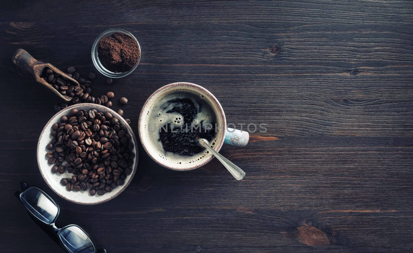 Delicious fresh coffee. Coffee cup, coffee beans, ground powder and glasses on vintage wood table background. Flat lay.