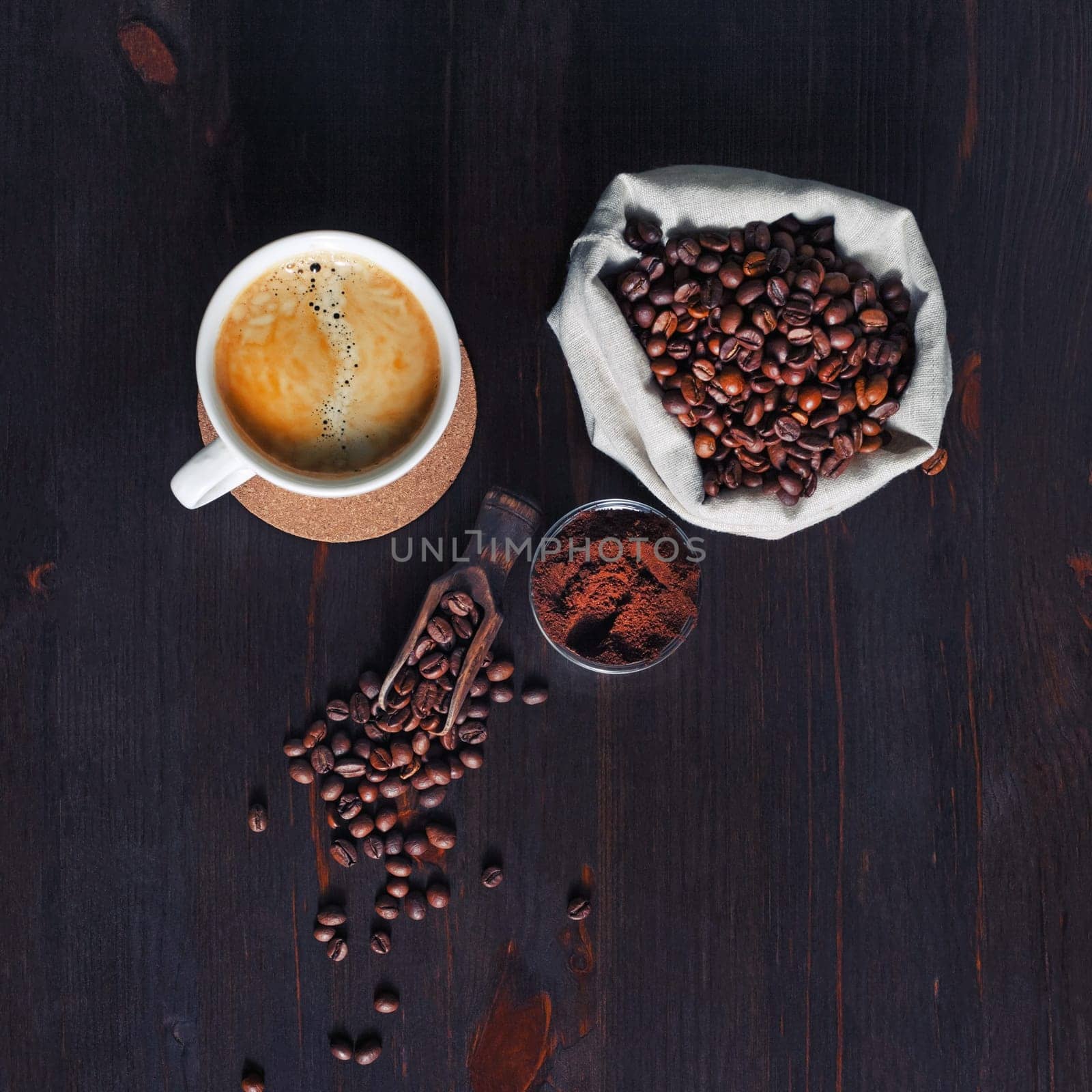 Brewing coffee still life. Coffee cup, coffee beans in canvas bag and ground powder on wood kitchen table background. Top view. Flat lay.