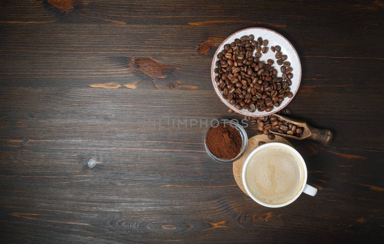 Photo of coffee cup, roasted coffee beans and ground powder on wooden table background. Copy space for your text. Top view. Flat lay.