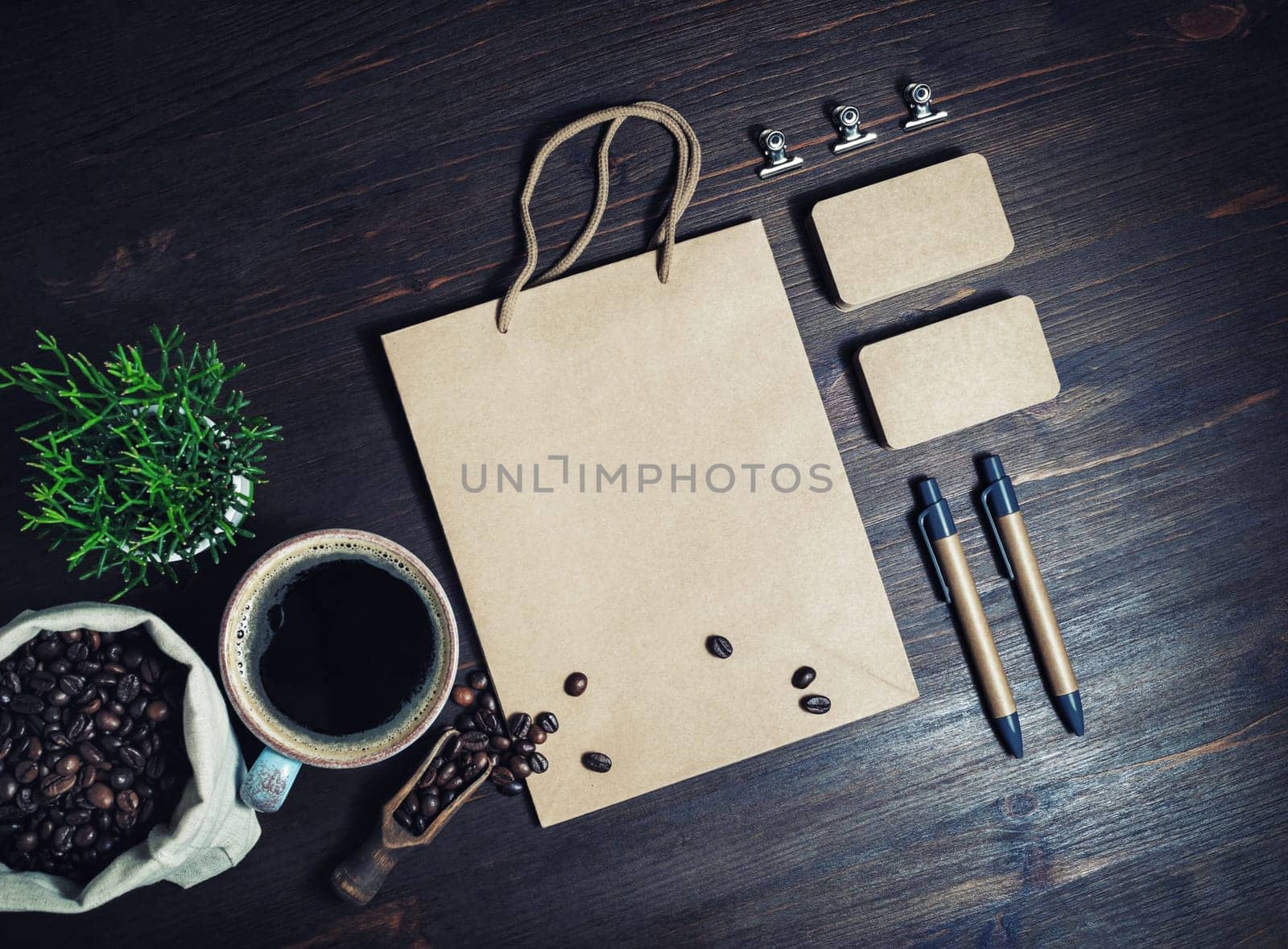 Photo of blank kraft paper stationery set and coffee on vintage wooden background. Template for placing your design. Top view. Flat lay.