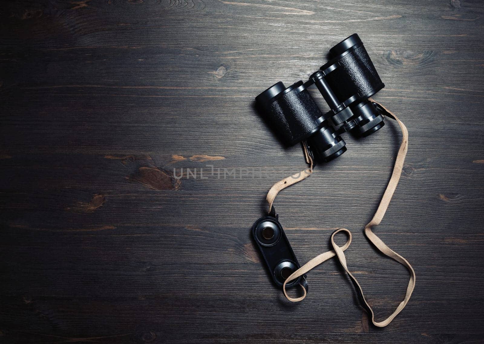 Photo of black vintage binocular on wooden background. Top view. Flat lay.