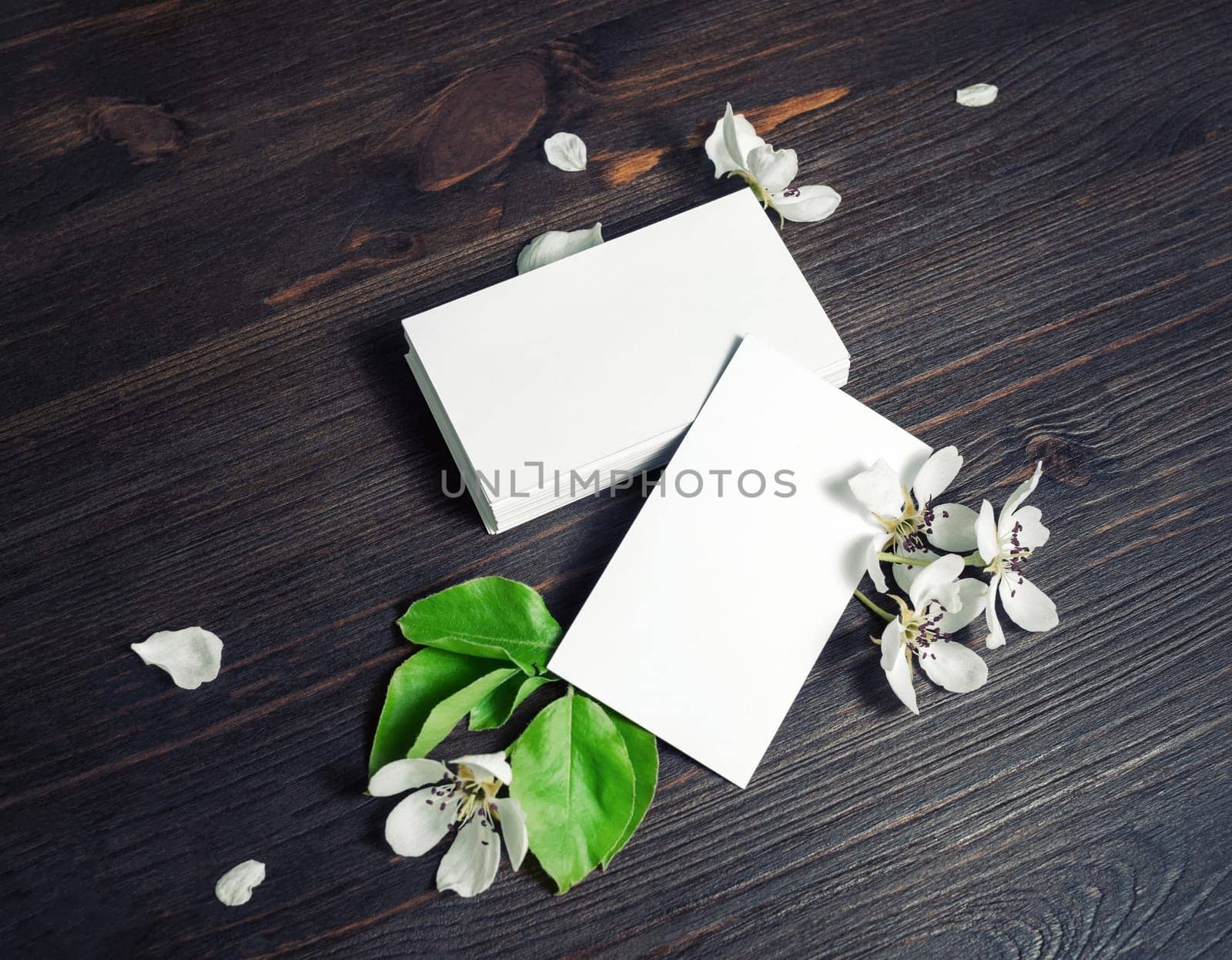 Photo of blank white business cards and flowers on wooden background. Branding ID template.
