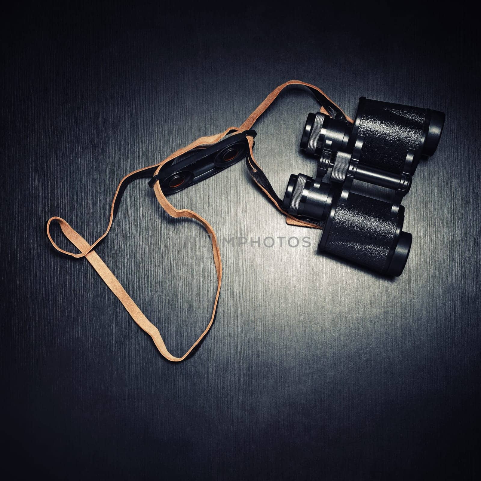Vintage black binocular on black wooden background. Top view. Flat lay.