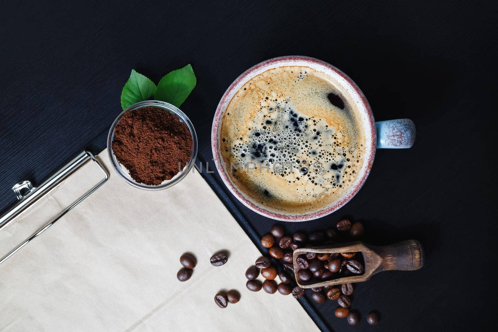 Still life with coffee on black table background. Coffee cup, coffee beans and ground powder. Flat lay.