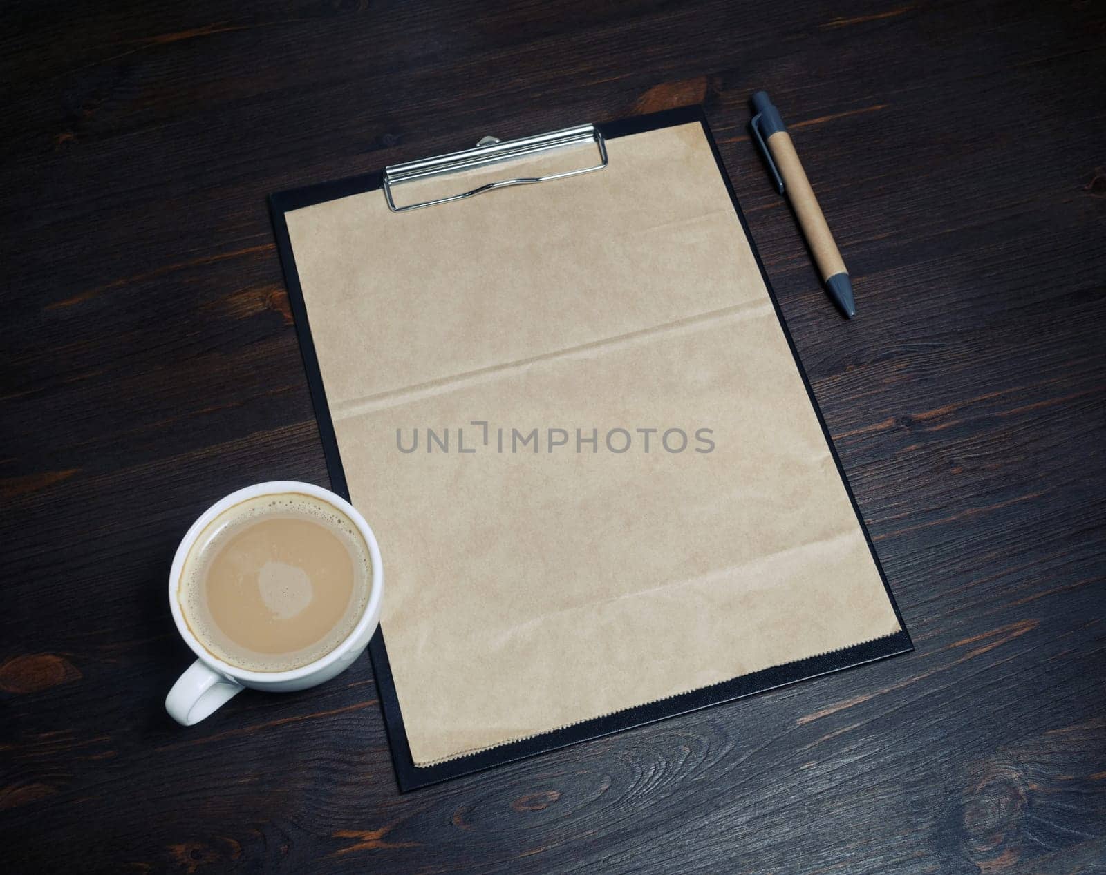Blank vintage stationery. Clipboard with kraft paper letterhead, coffee cup and pen on wooden background. Responsive design template.