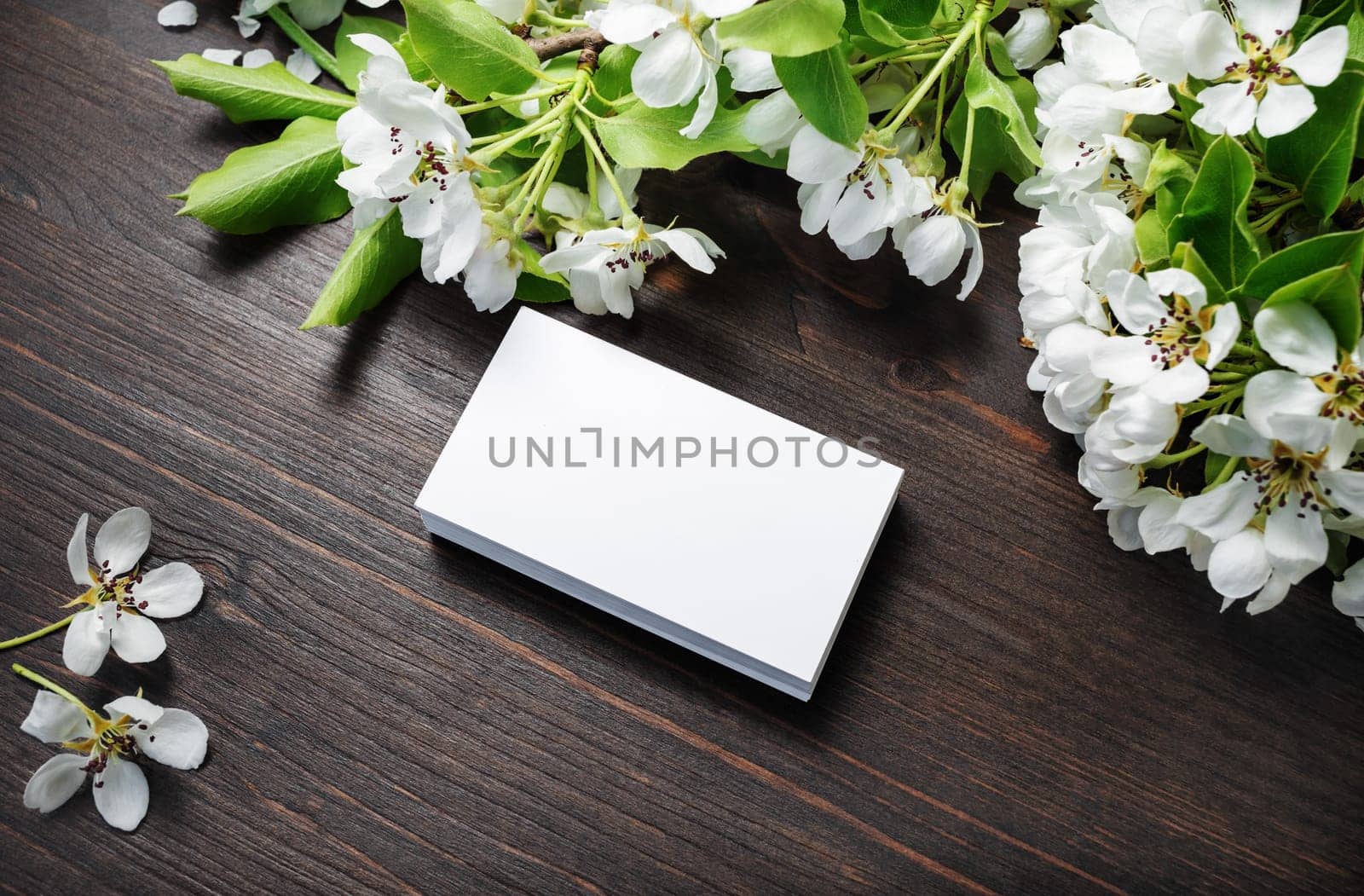 Blank business cards and flowers on wood table background. Mockup for branding identity. Studio shot.