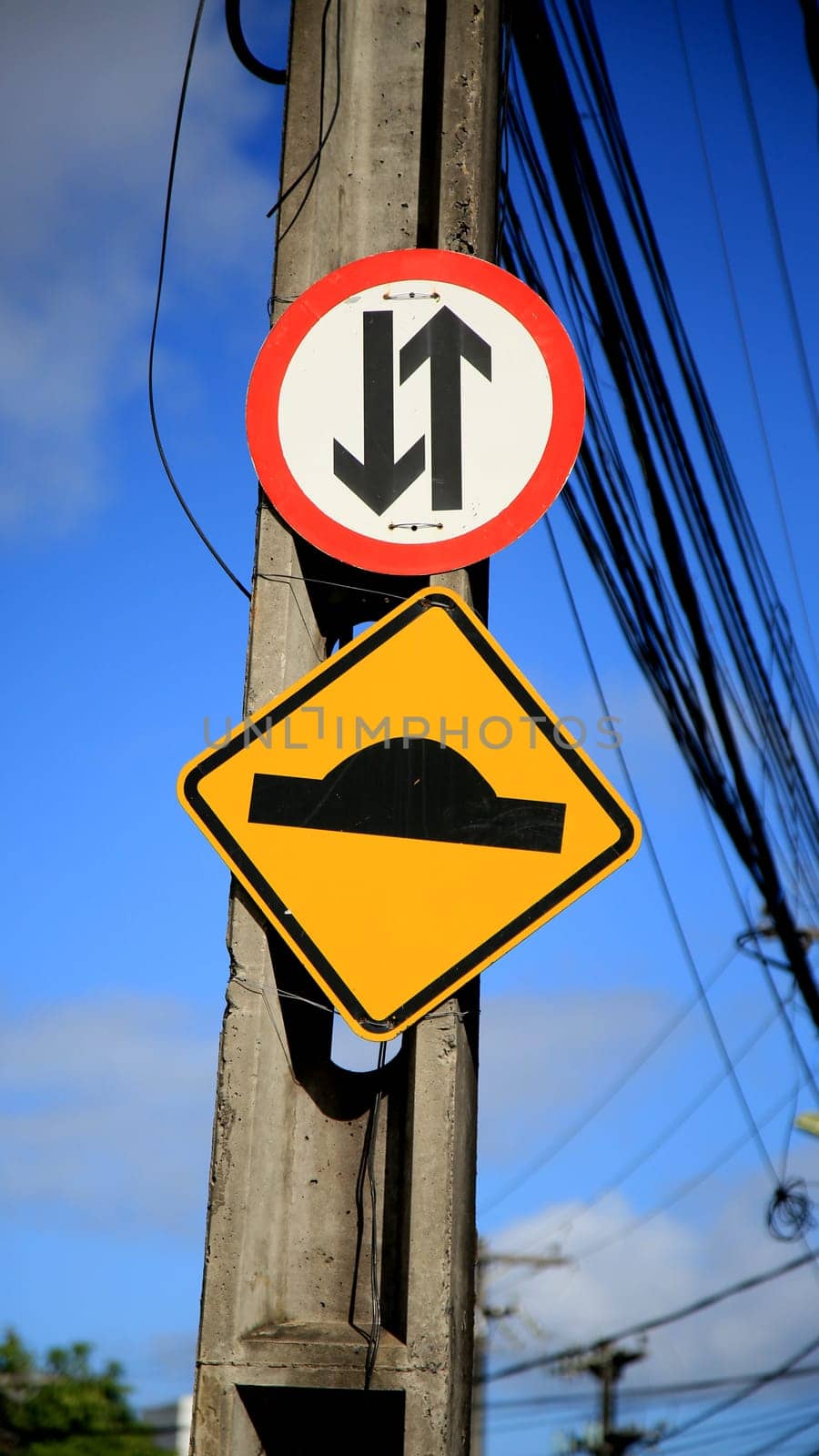 salvador, bahia / brazil - july 4, 2020: traffic signs indicate speed bumps and two-way street are seen on a pole connected to the power grid in the Cabula neighborhood in the city of Salvador...