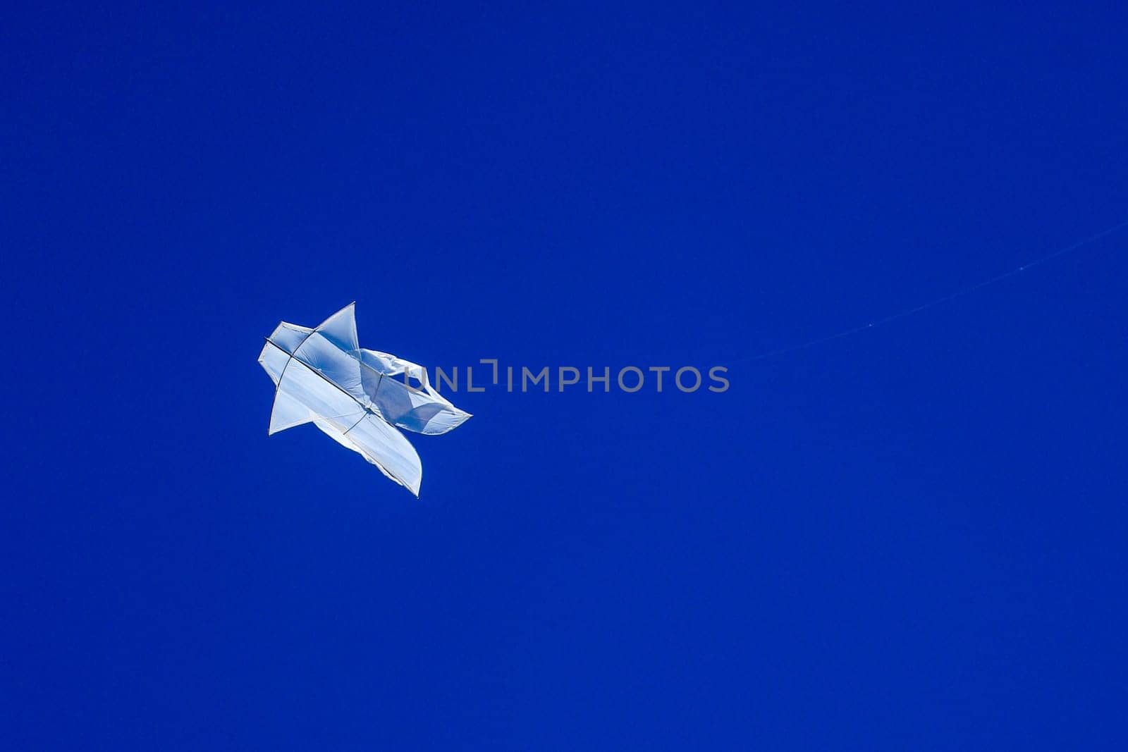 The Balinese white kite flies against the blue sky. Blue sky is the perfect background for kites. space for your text..