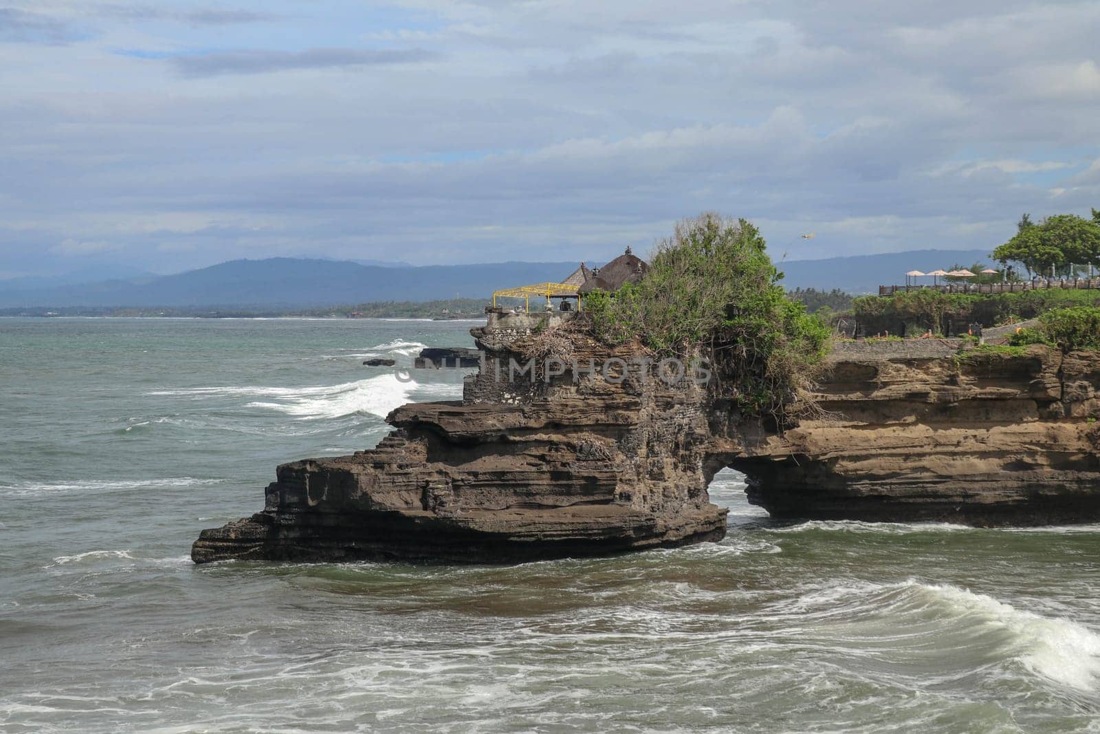 Batu Bolong beach which has an tourism attraction spot close to Tanah Lot temple. Huge hole in rock cliff below Pura Batu Bolong temple. Hindu Temple on the Beatiful Rock in the morning light, Bali.