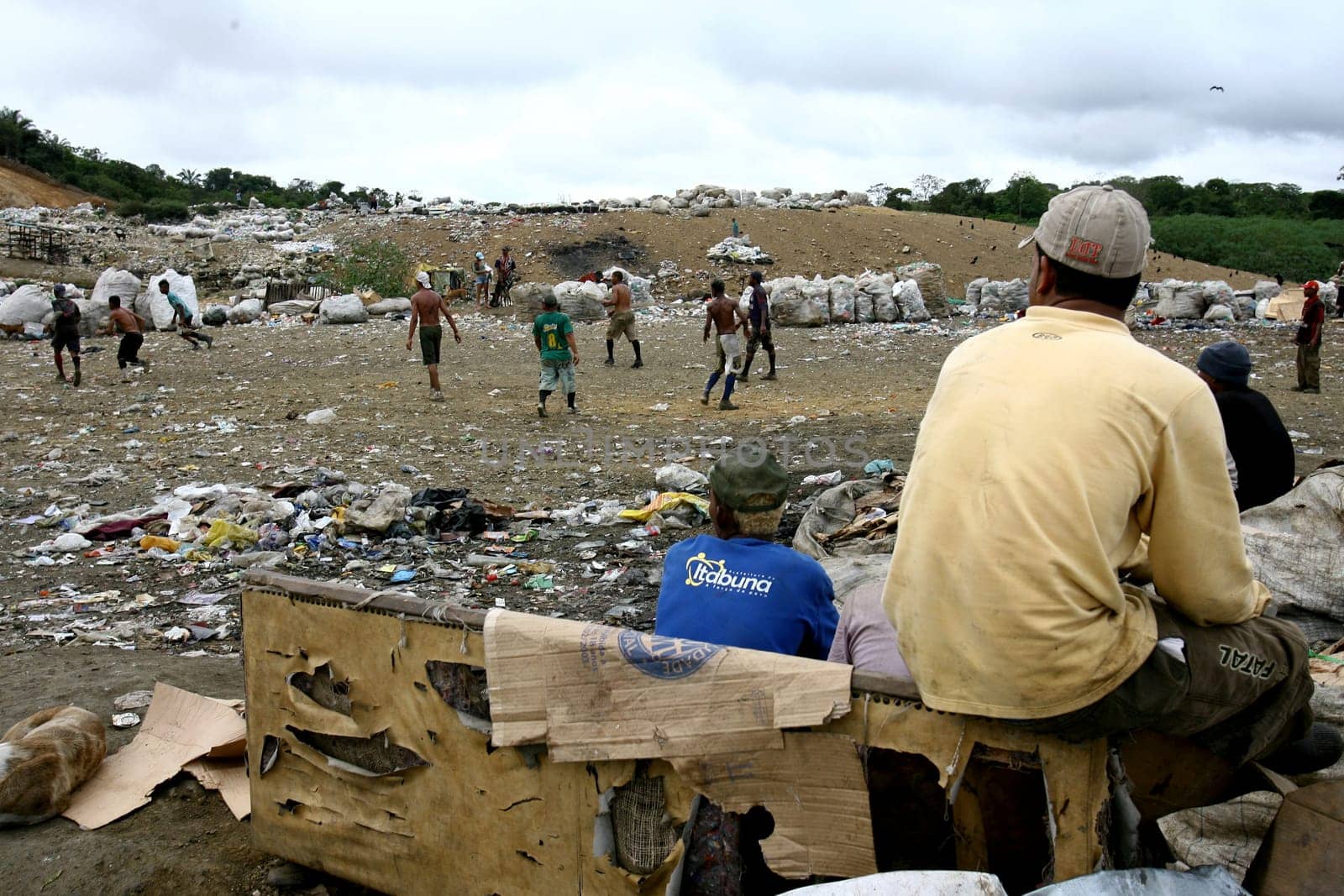 itabuna, bahia / brazil - september 22, 2011: waste pickers watch their colleagues playing football at the sanitary landfill in the city of Itabuna.